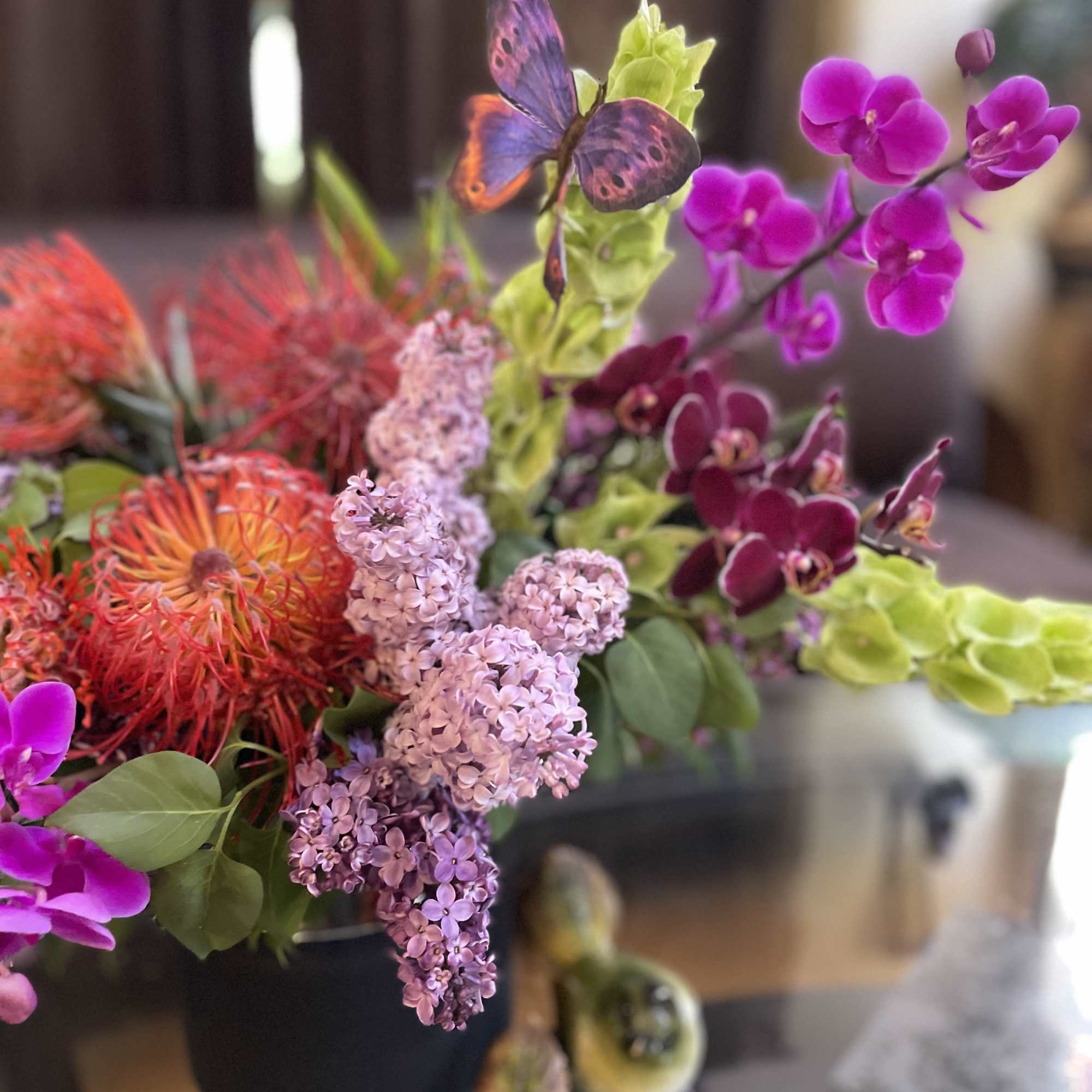 Bright mixed bouquet with orchids, lilac, and orange pincushion blooms