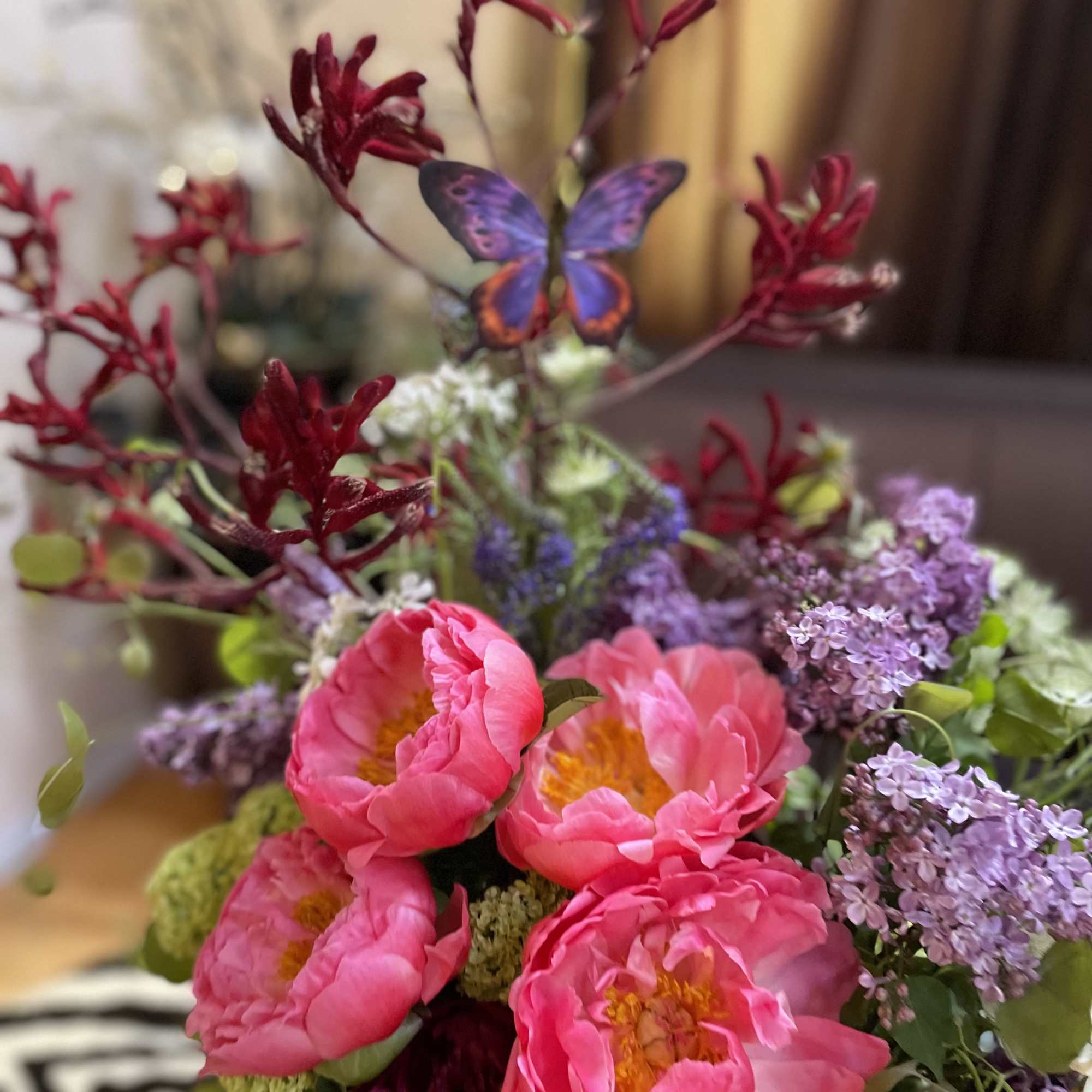 Bouquet of pink peonies and purple lilacs with a butterfly accent