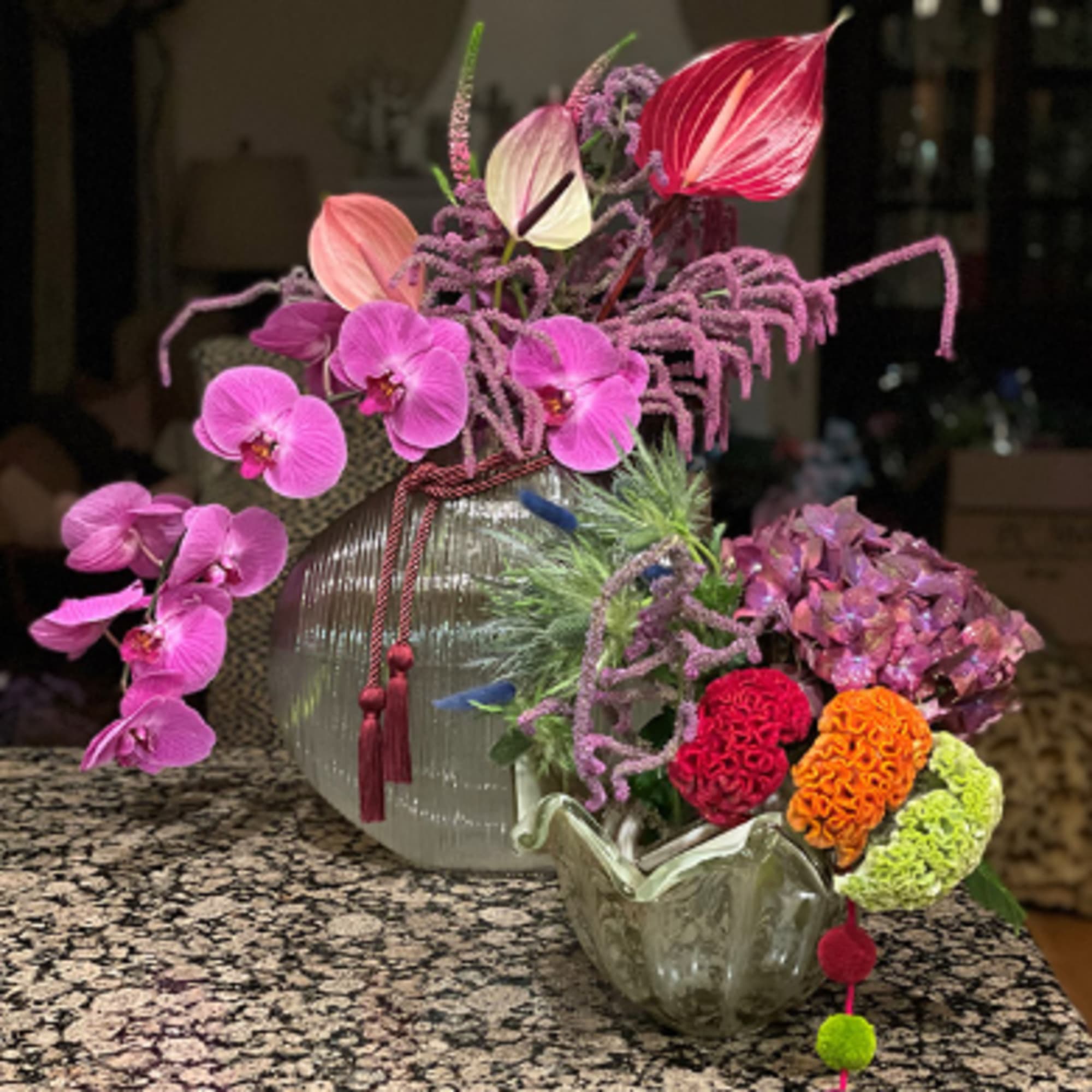 Pink orchids and colorful blooms arranged in a glass vase