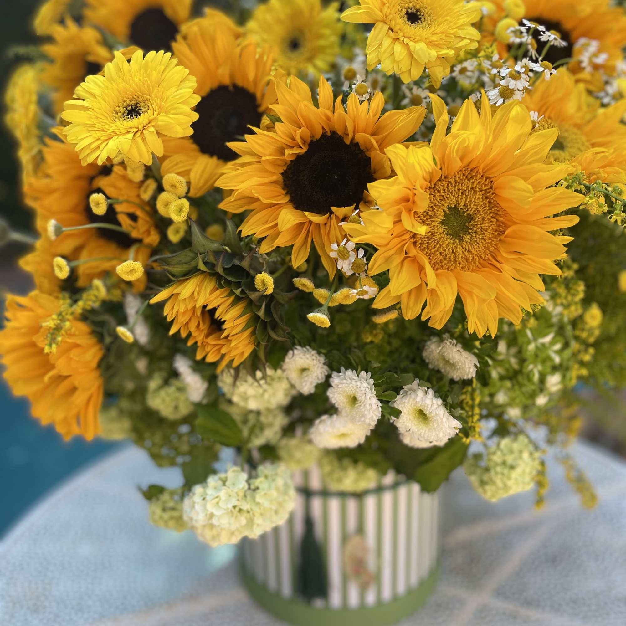 Bouquet of yellow sunflowers and white daisies in a striped vase