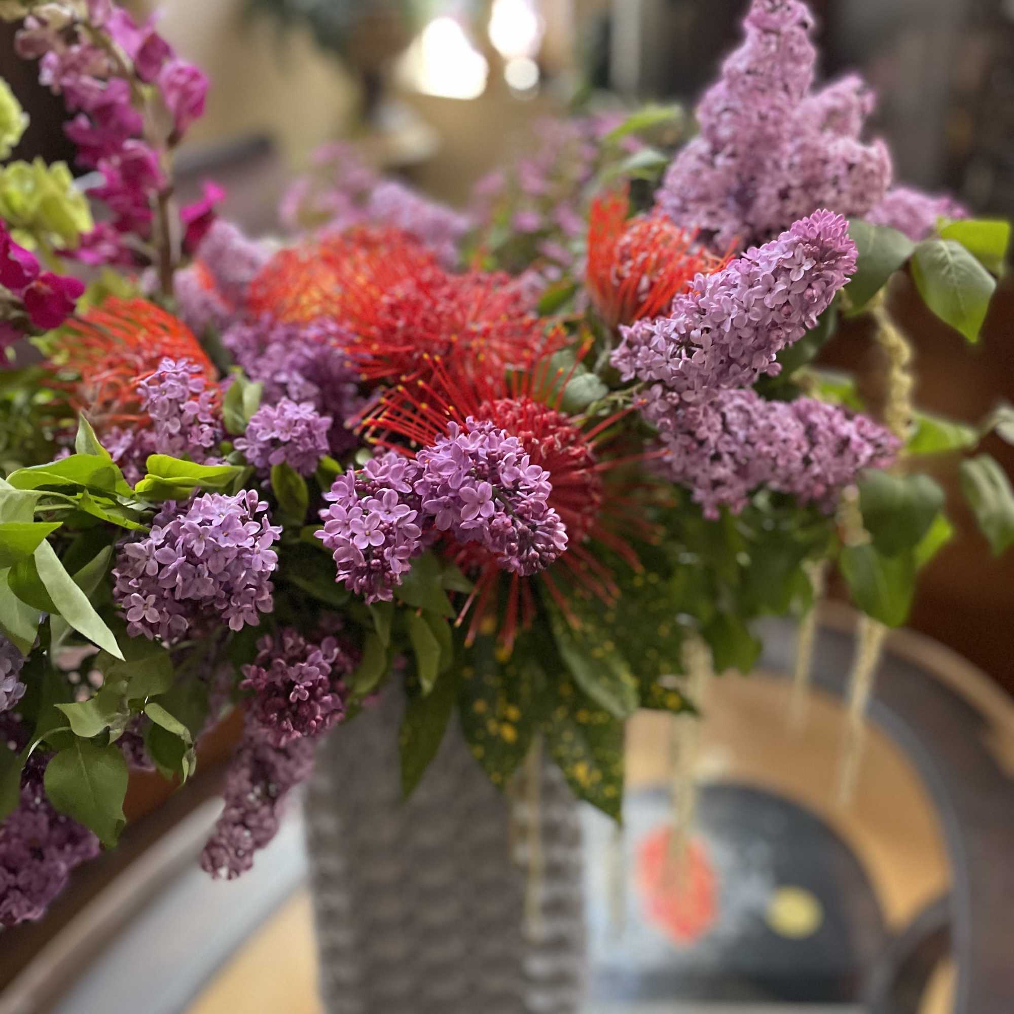 Lilac and red floral arrangement in a tall vase
