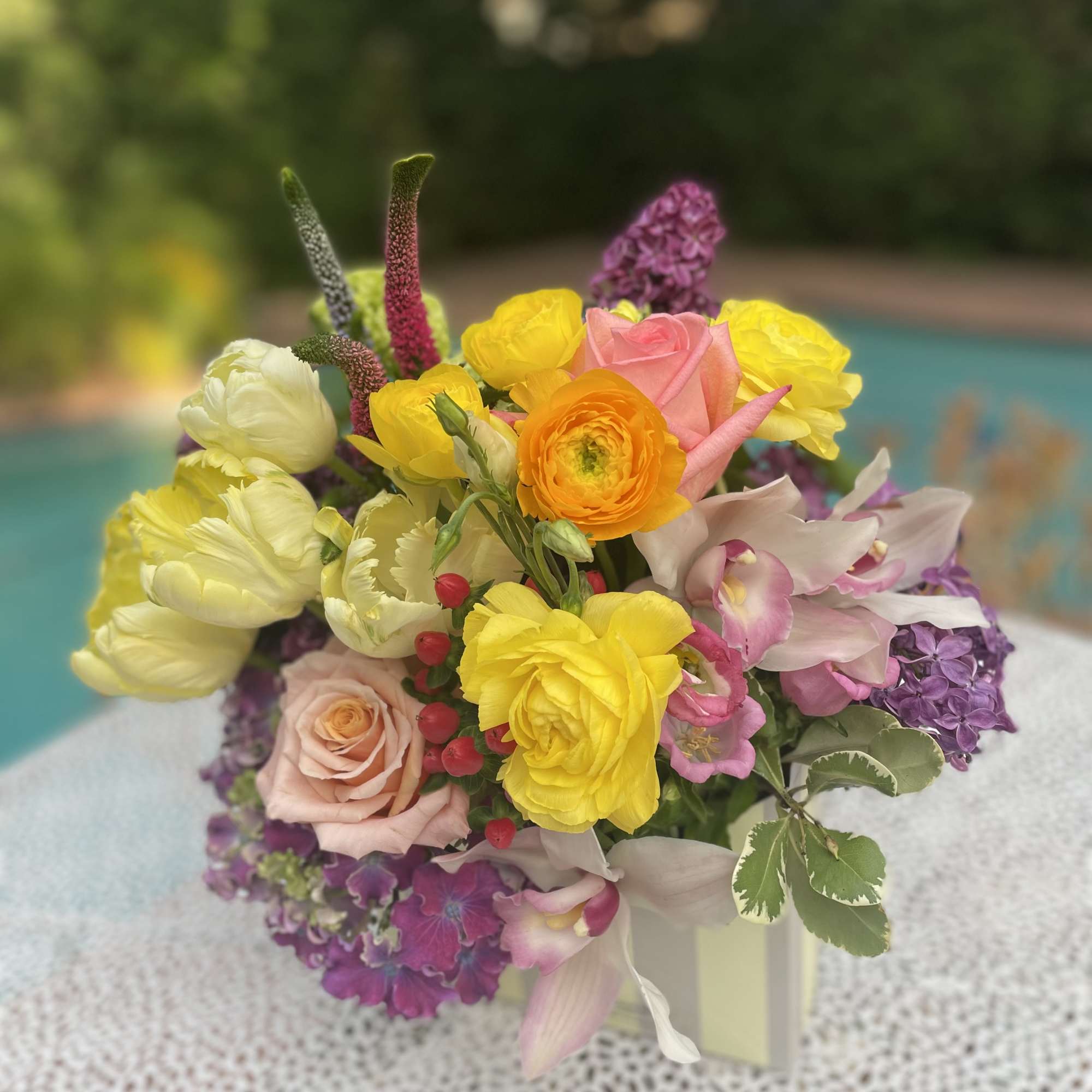 Colorful bouquet of roses, ranunculus, tulips, and orchids in a vase