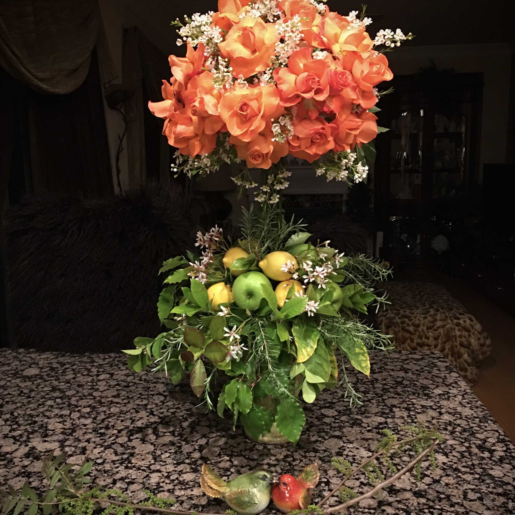 Orange rose arrangement with fruit and greenery in a vase