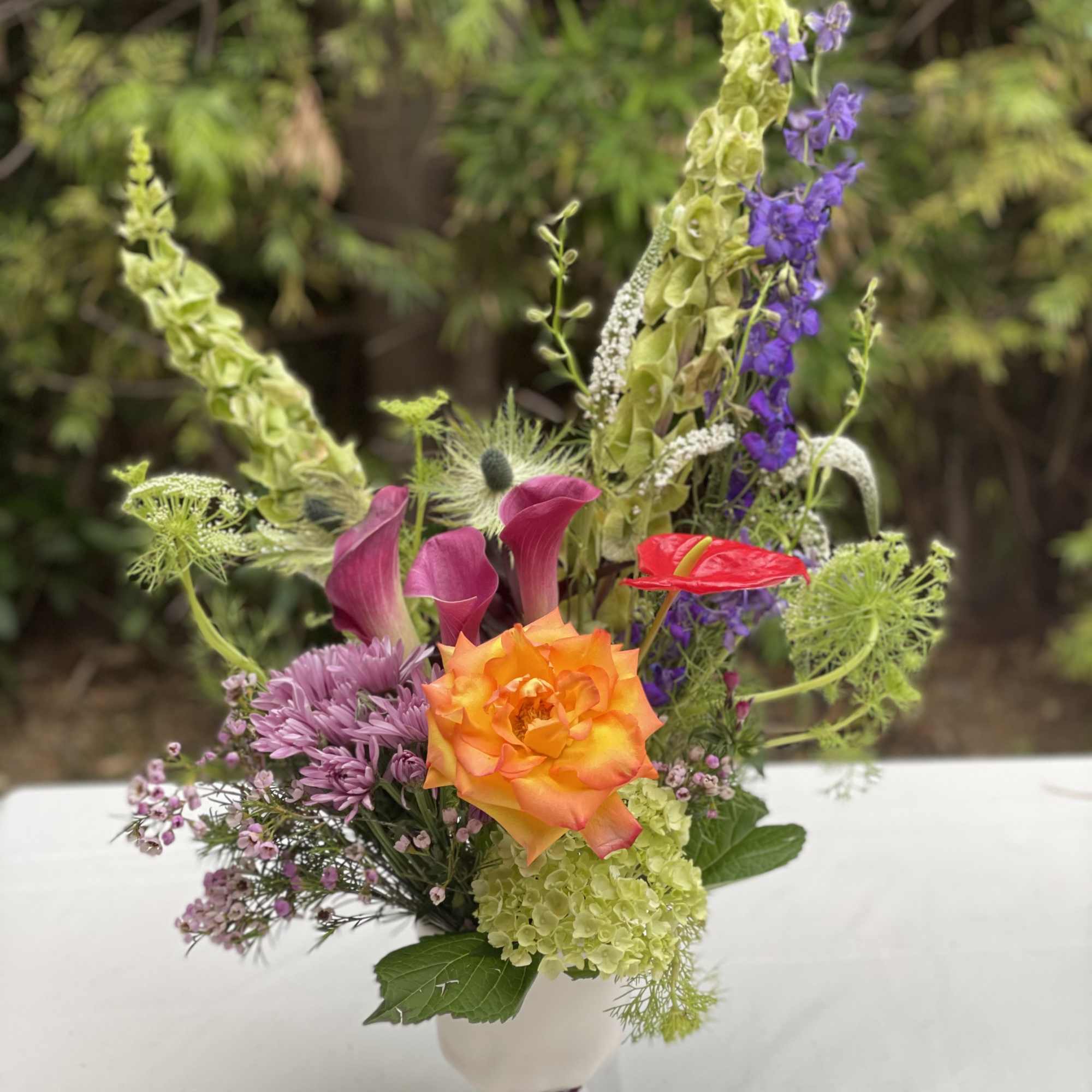 Colorful mixed bouquet in a white vase with tall purple and green blooms
