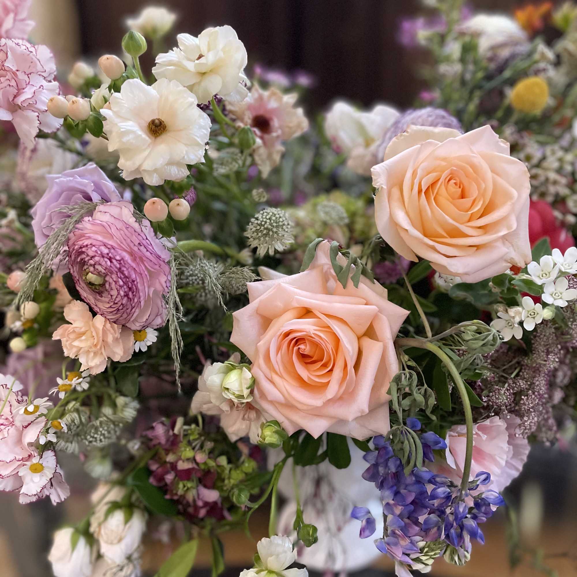 Pastel bouquet with peach roses, pink blooms, and purple flowers