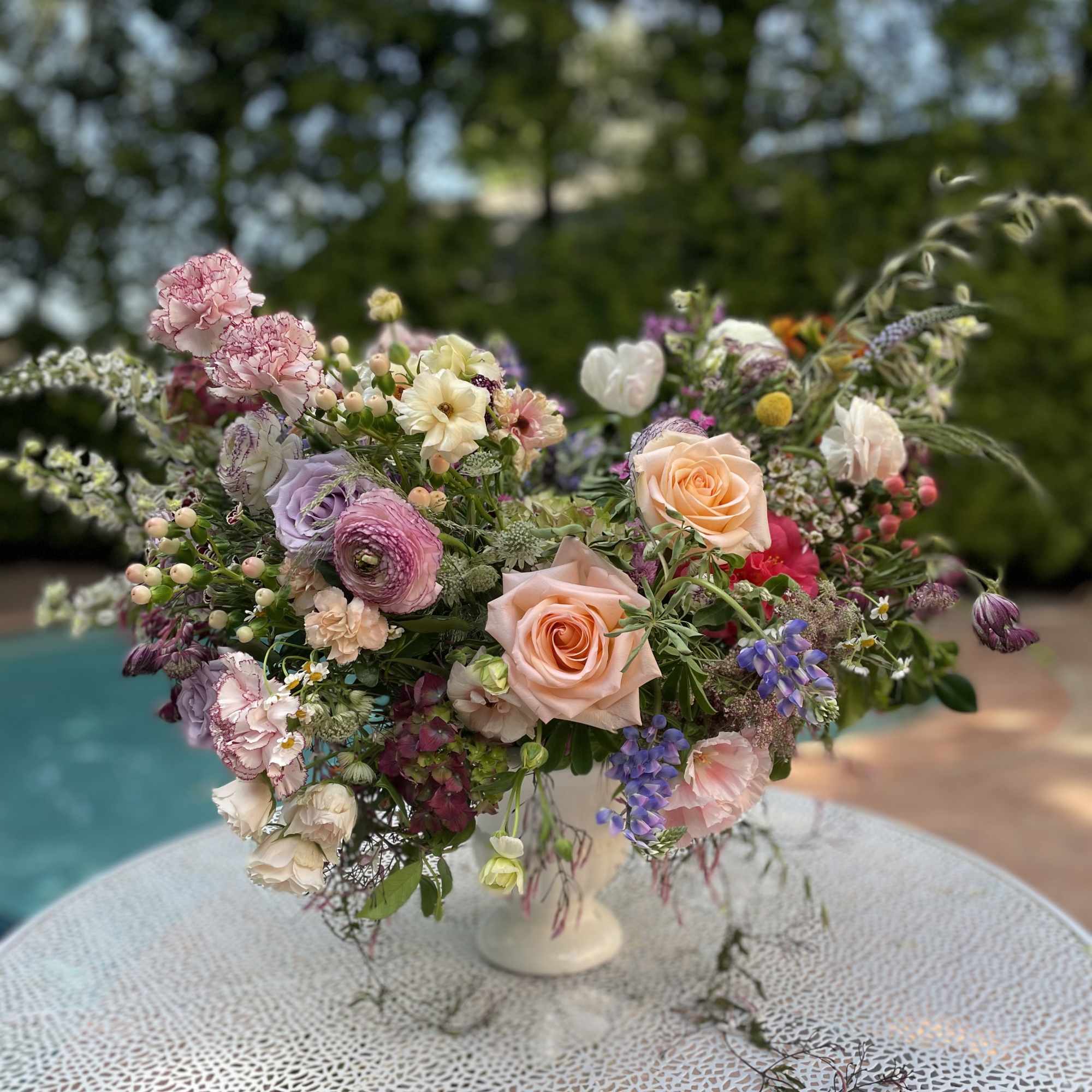 Pastel floral arrangement in a white pedestal vase on a table