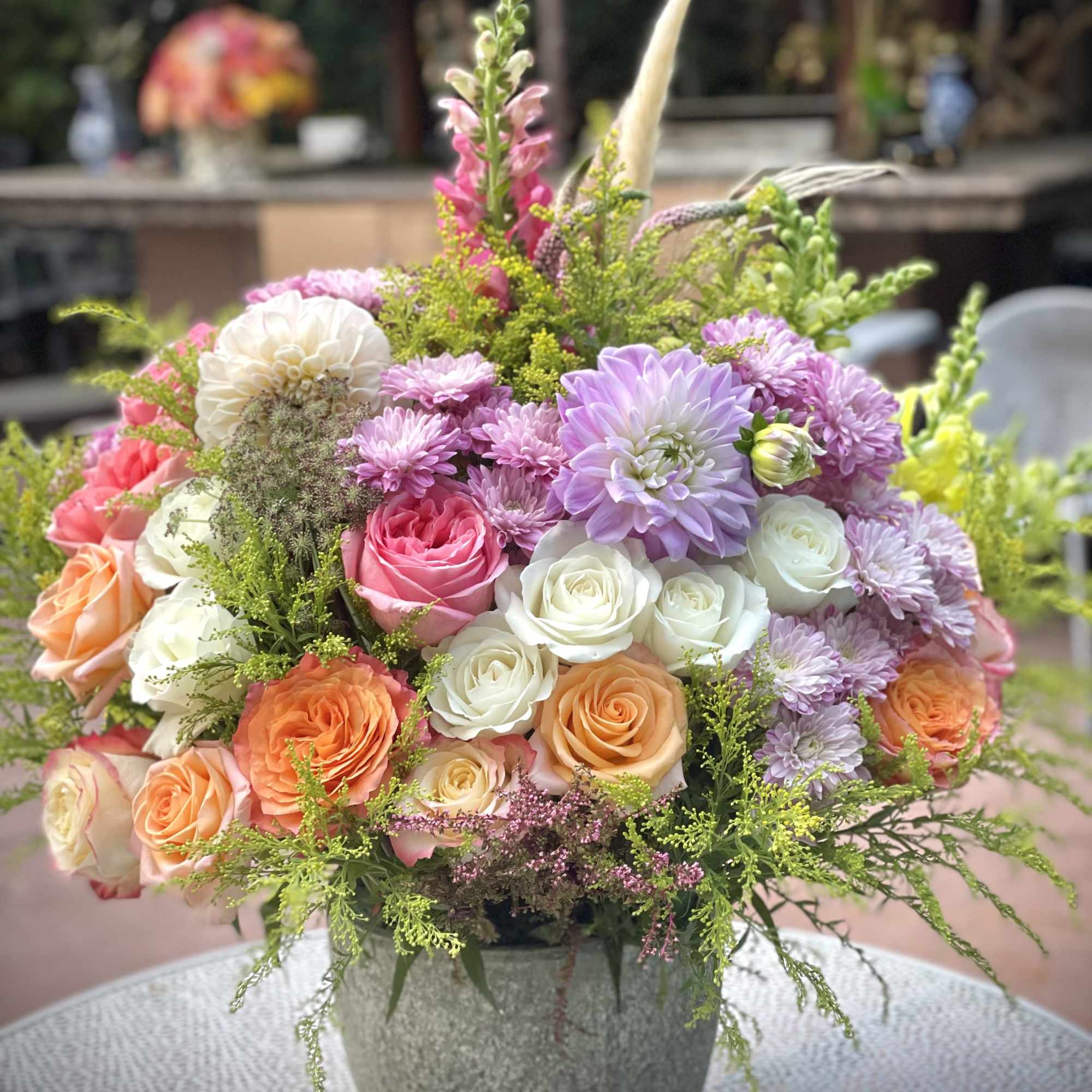 Mixed bouquet of roses and purple blooms in a gray vase