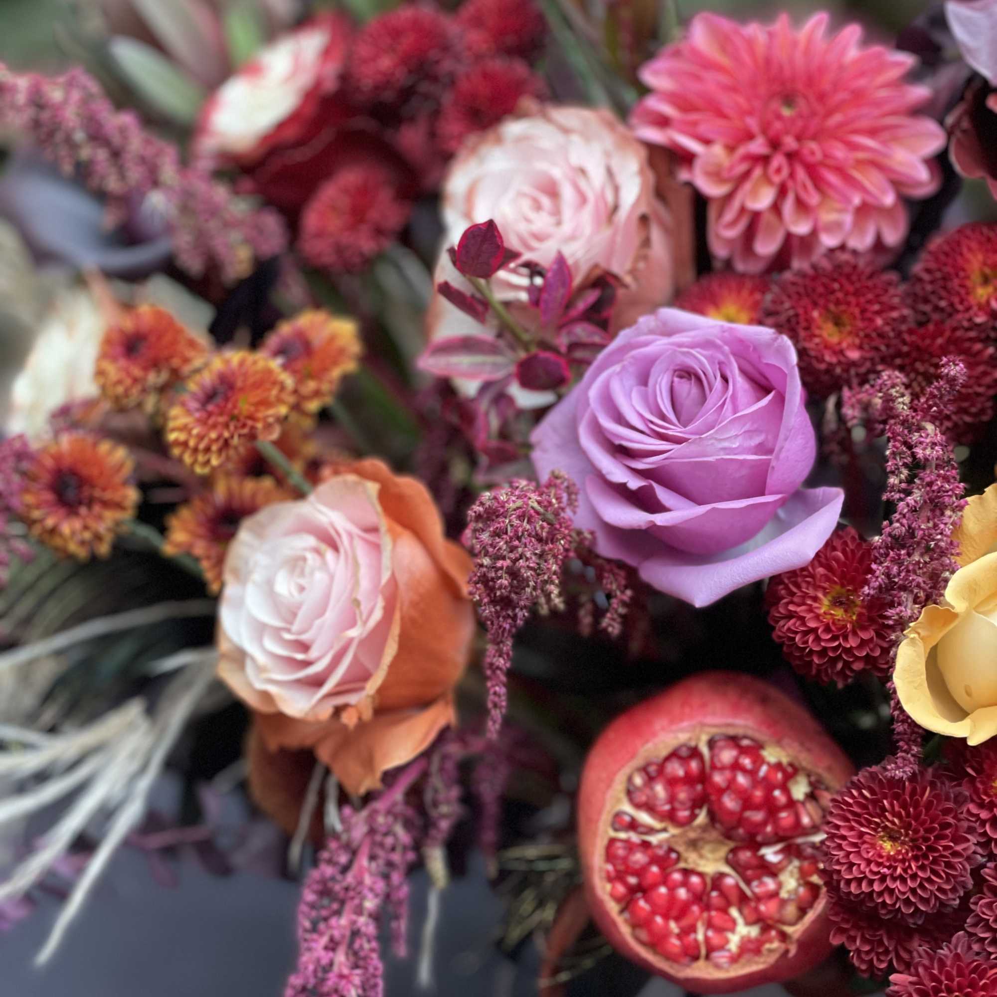Mixed bouquet with roses, dahlias, and a pomegranate slice