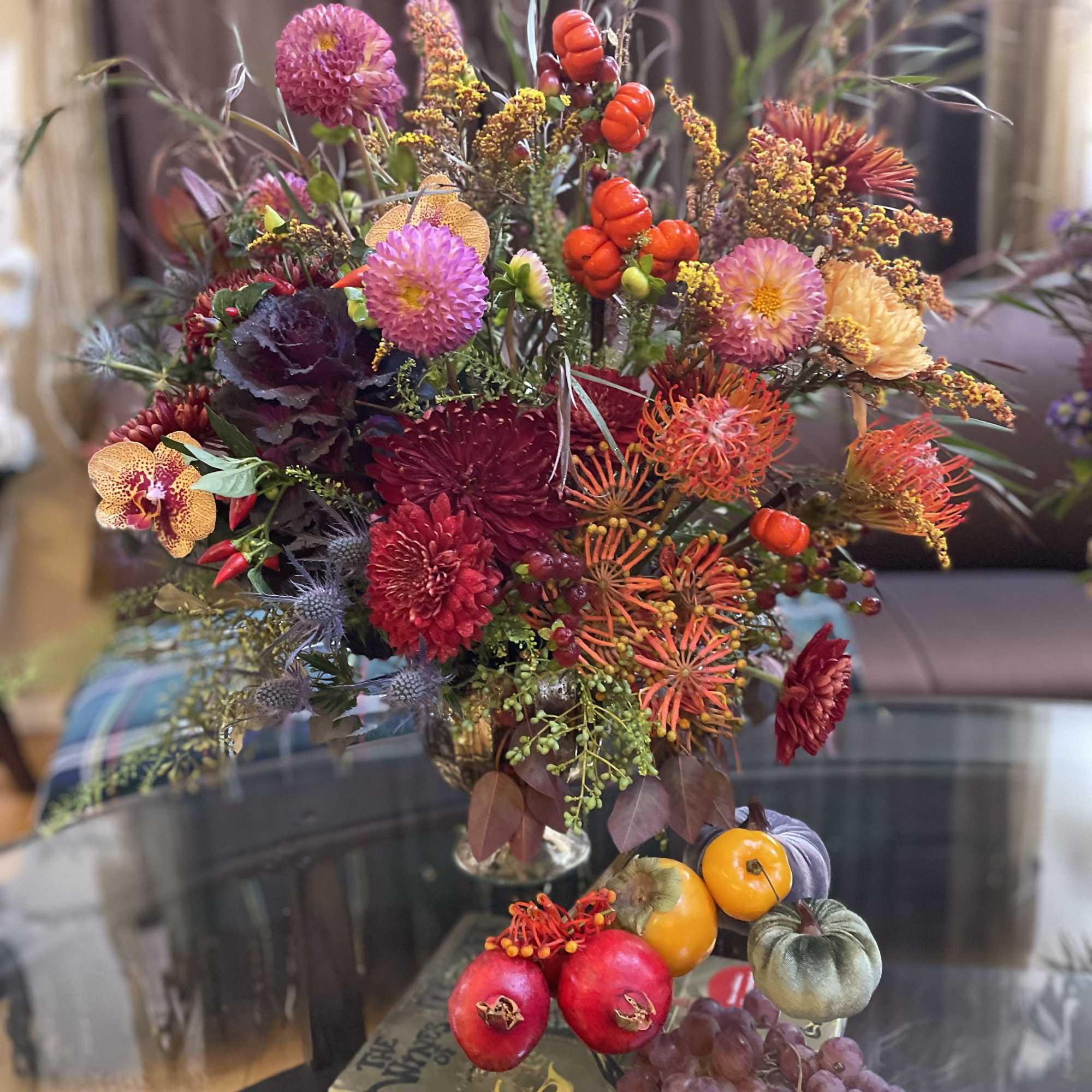 Colorful floral arrangement with pumpkins and grapes in a vase