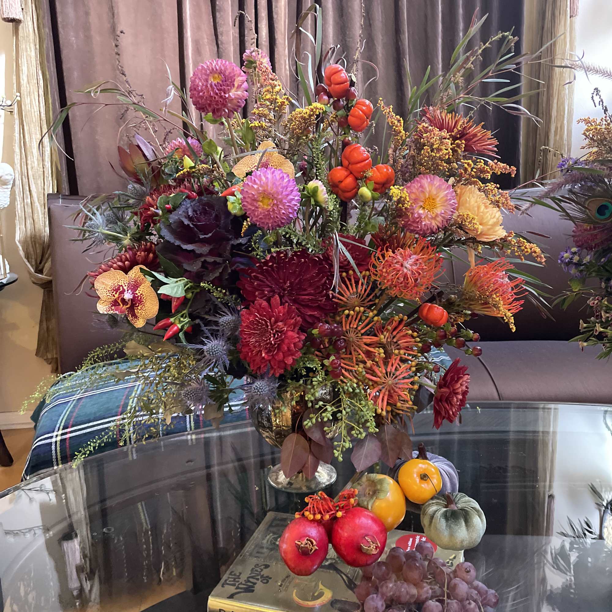 Large autumn floral arrangement with pumpkins and fruit on a table