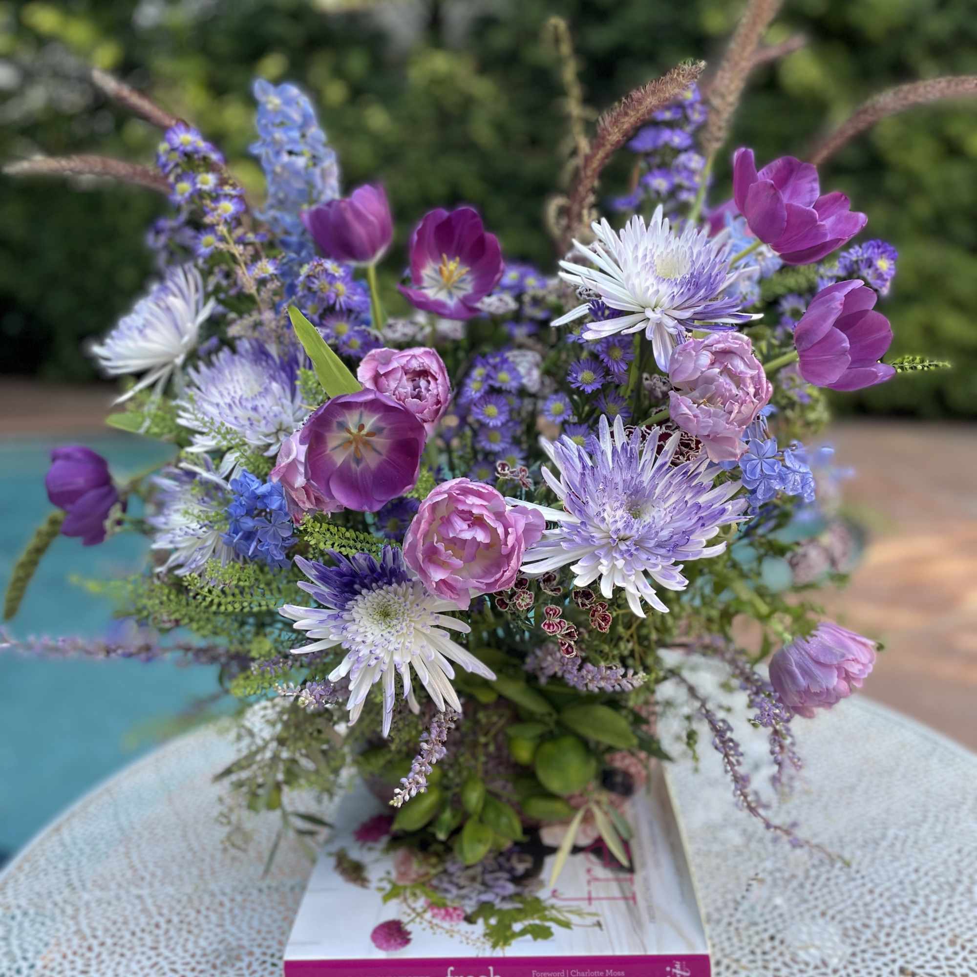 Mixed purple and pink bouquet in a vase on a book