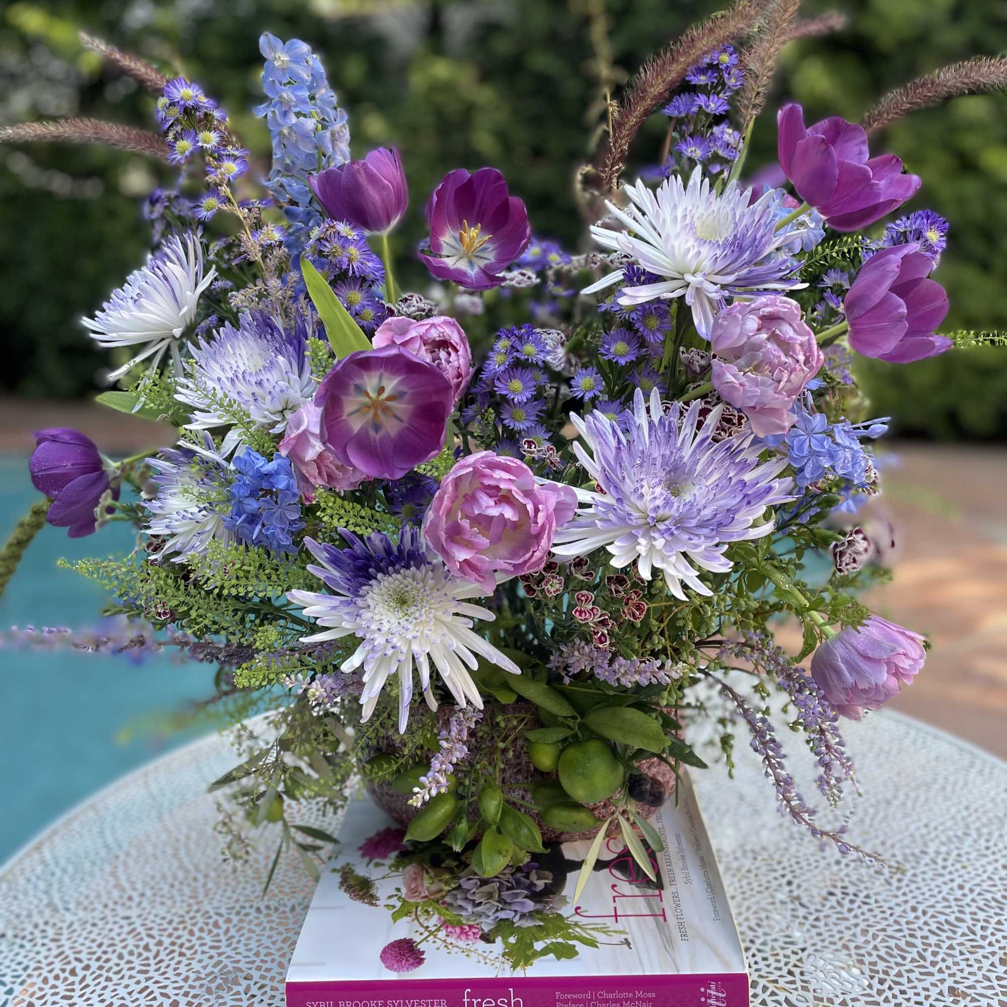 Mixed bouquet of purple, pink, and white flowers in a low container