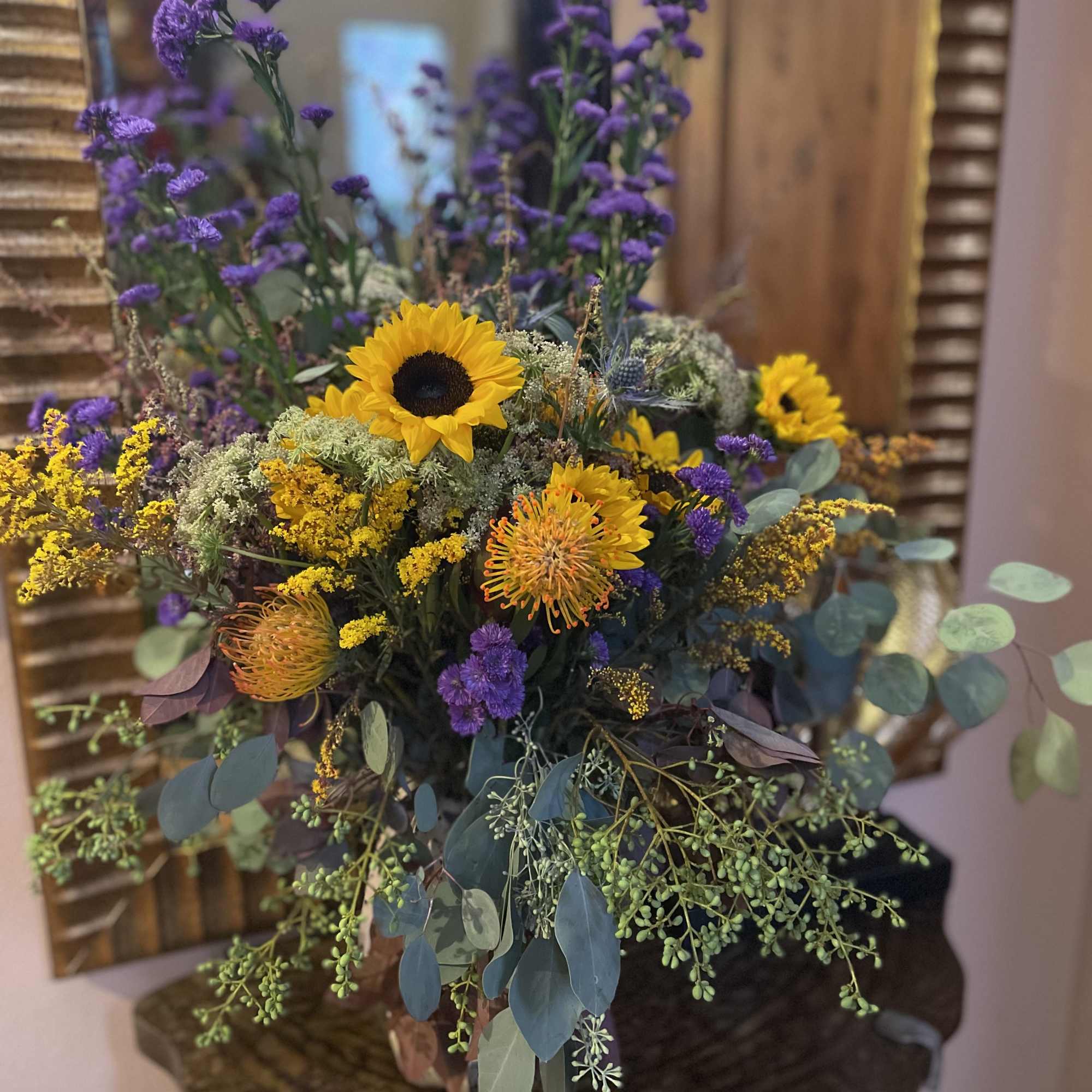 Bouquet with sunflowers, purple filler flowers, and eucalyptus in a vase