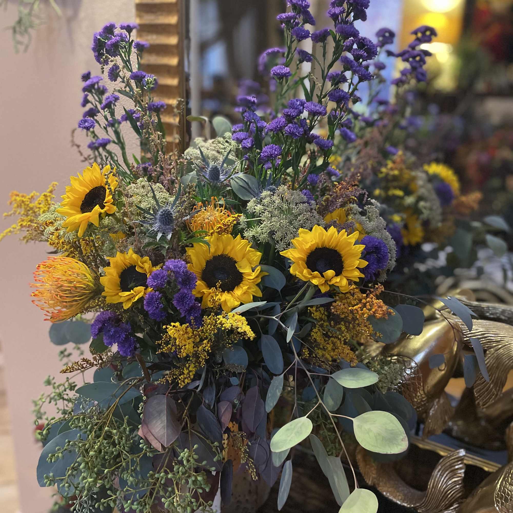 Bouquet with sunflowers and purple filler flowers in a decorative container