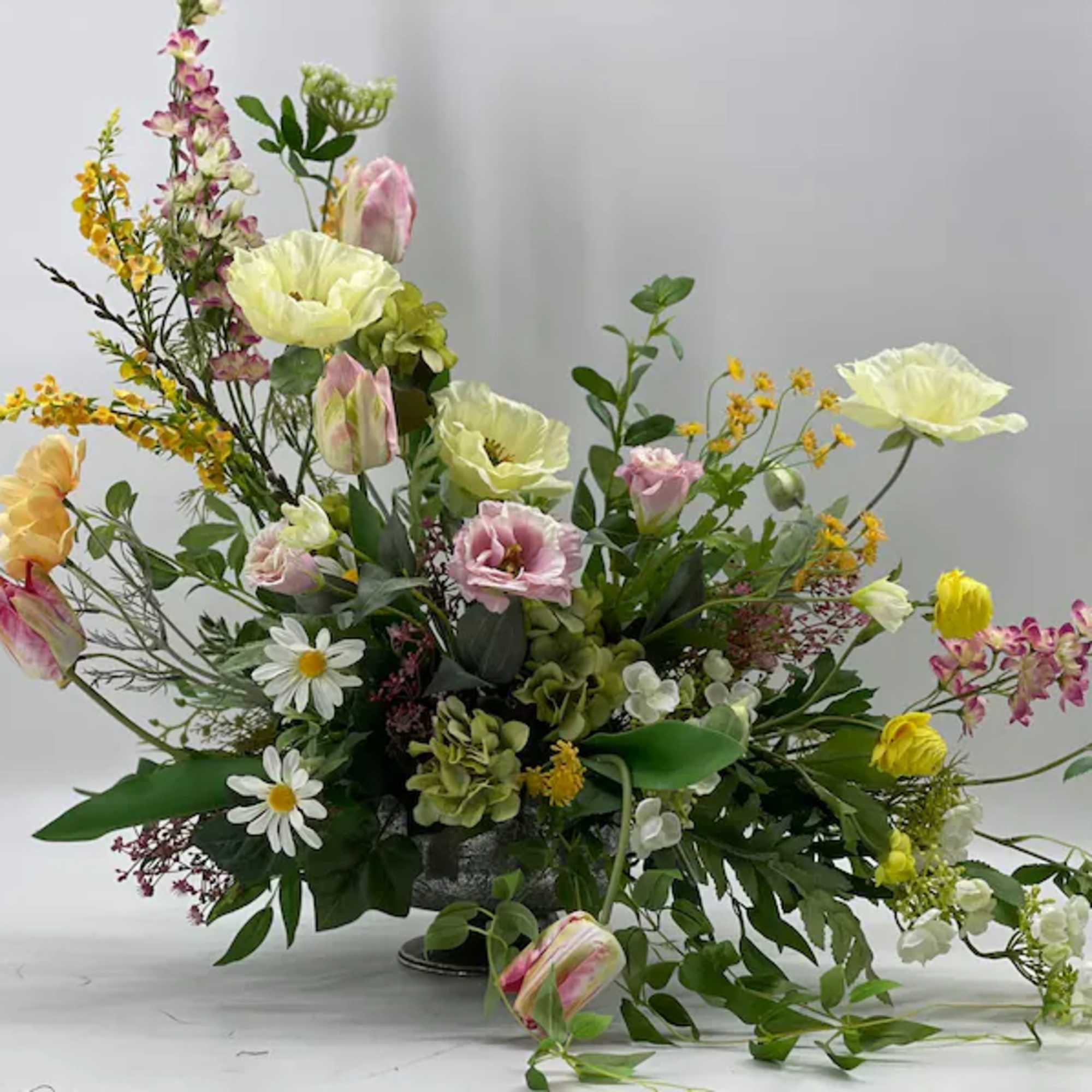 Mixed floral arrangement with pastel blooms in a low container
