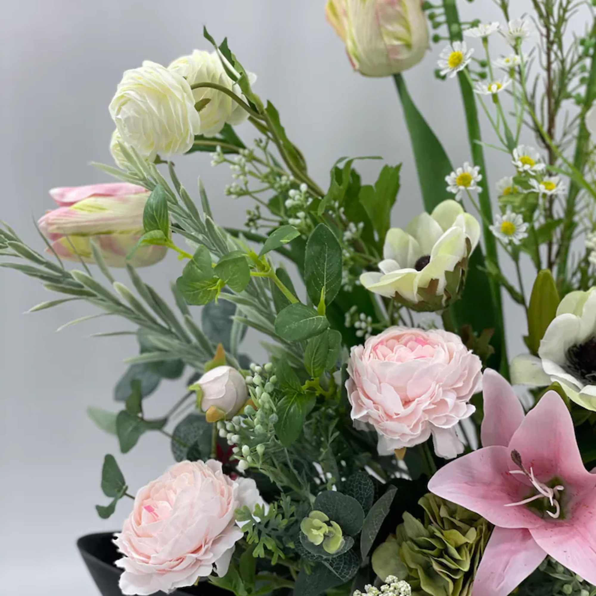 Mixed bouquet with pink and white flowers in a black container
