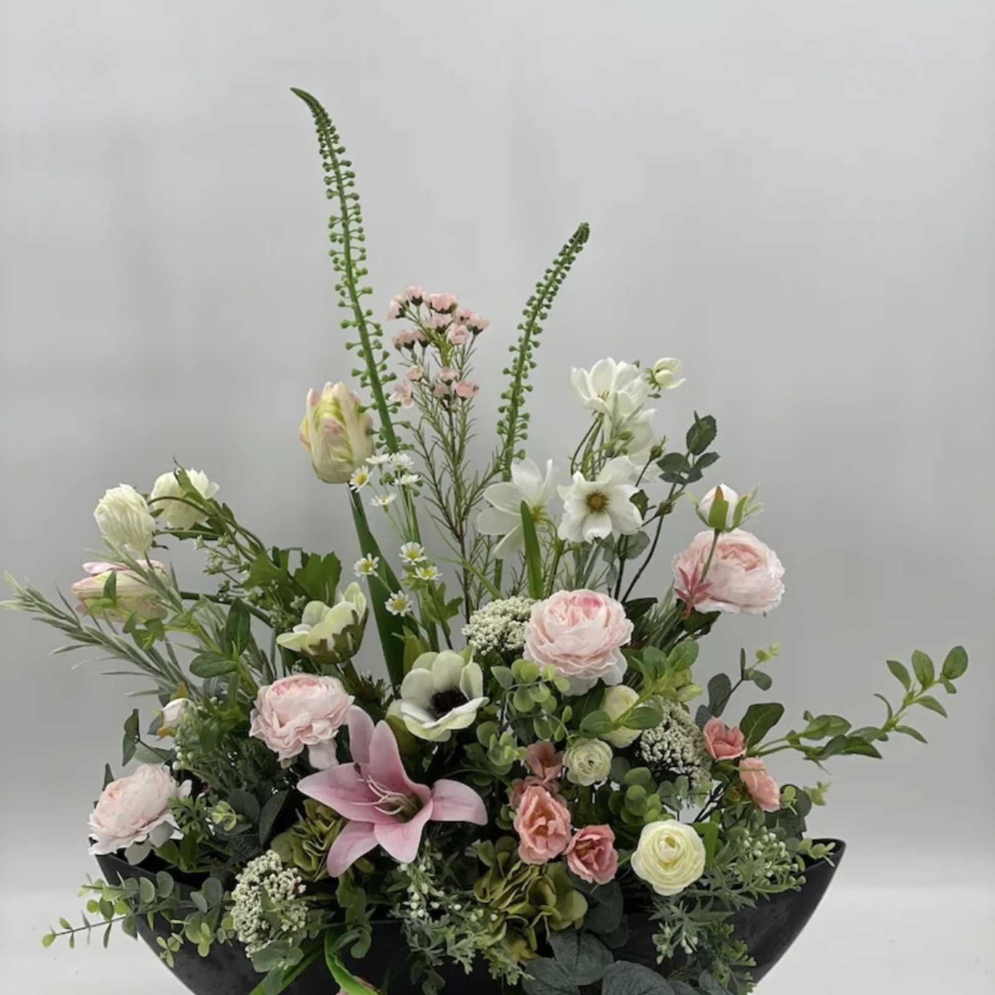 Mixed pink and white floral arrangement in a black bowl vase