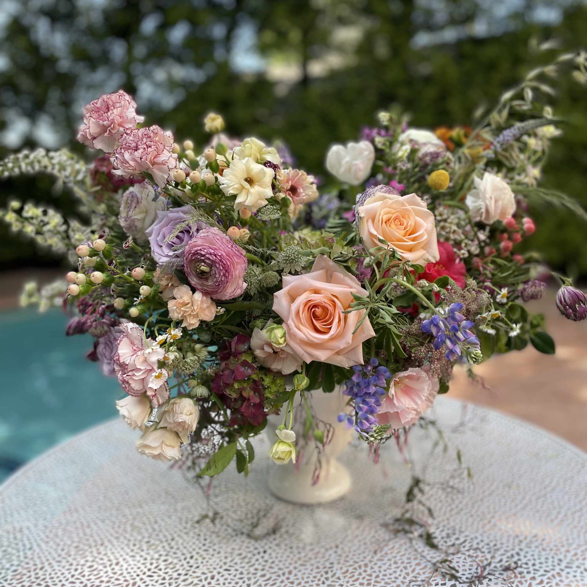 Mixed pastel flower arrangement in a white pedestal vase