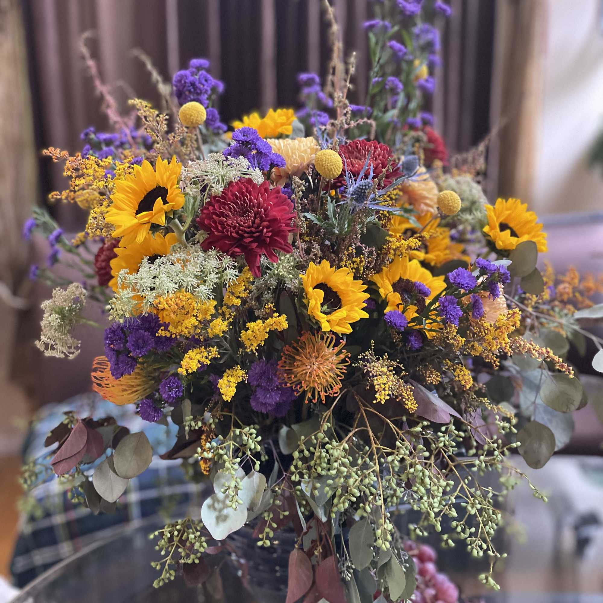 Large mixed bouquet with sunflowers, purple blooms, and eucalyptus in a vase