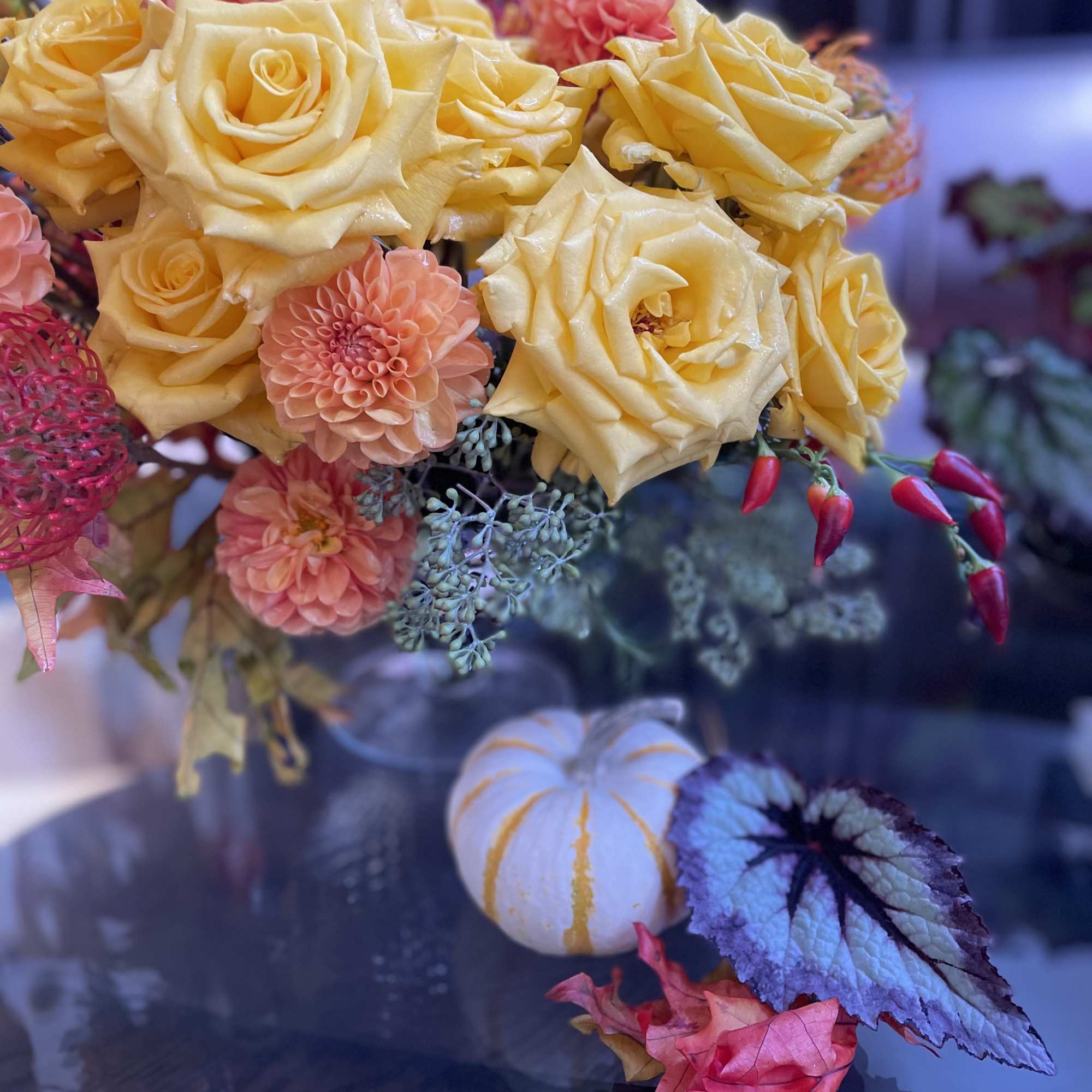 Yellow roses and peach dahlias in a bouquet with decorative foliage