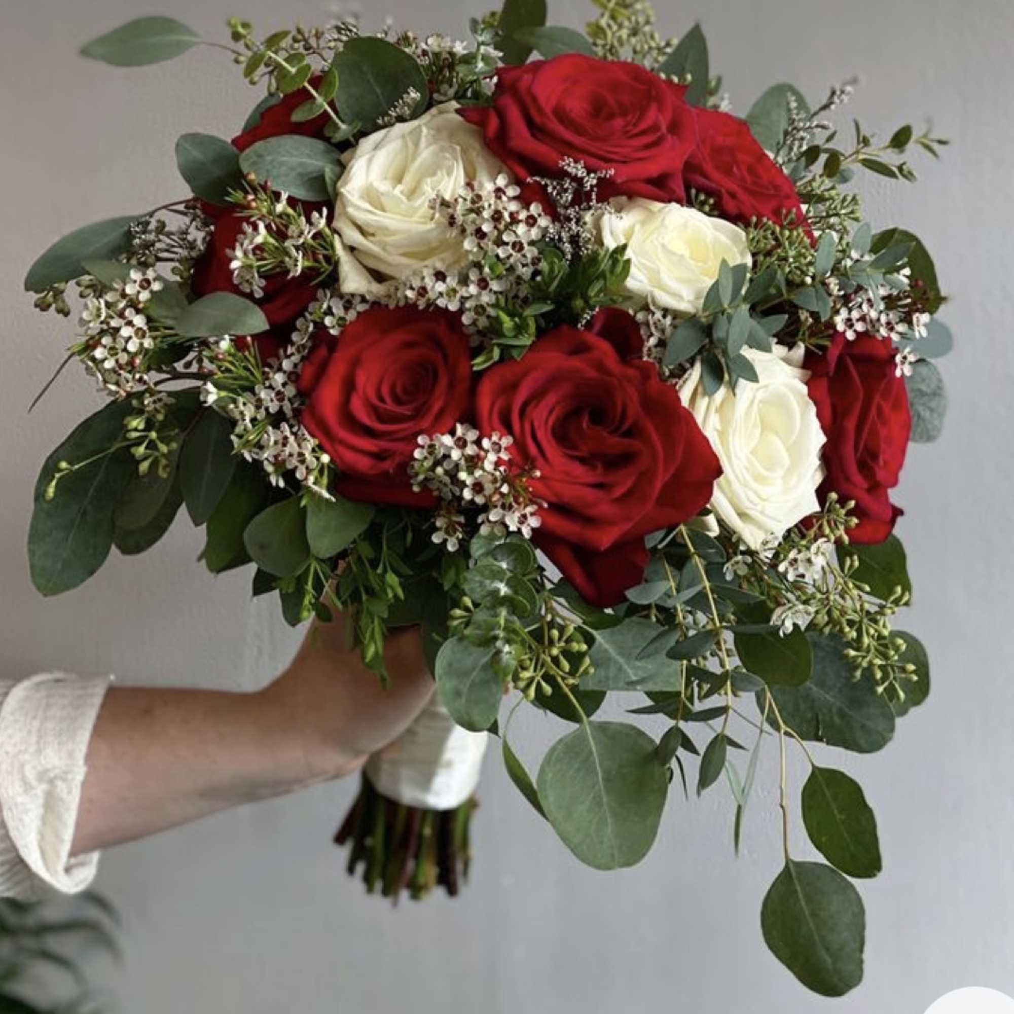 Bouquet of red and white roses with greenery and small white filler flowers