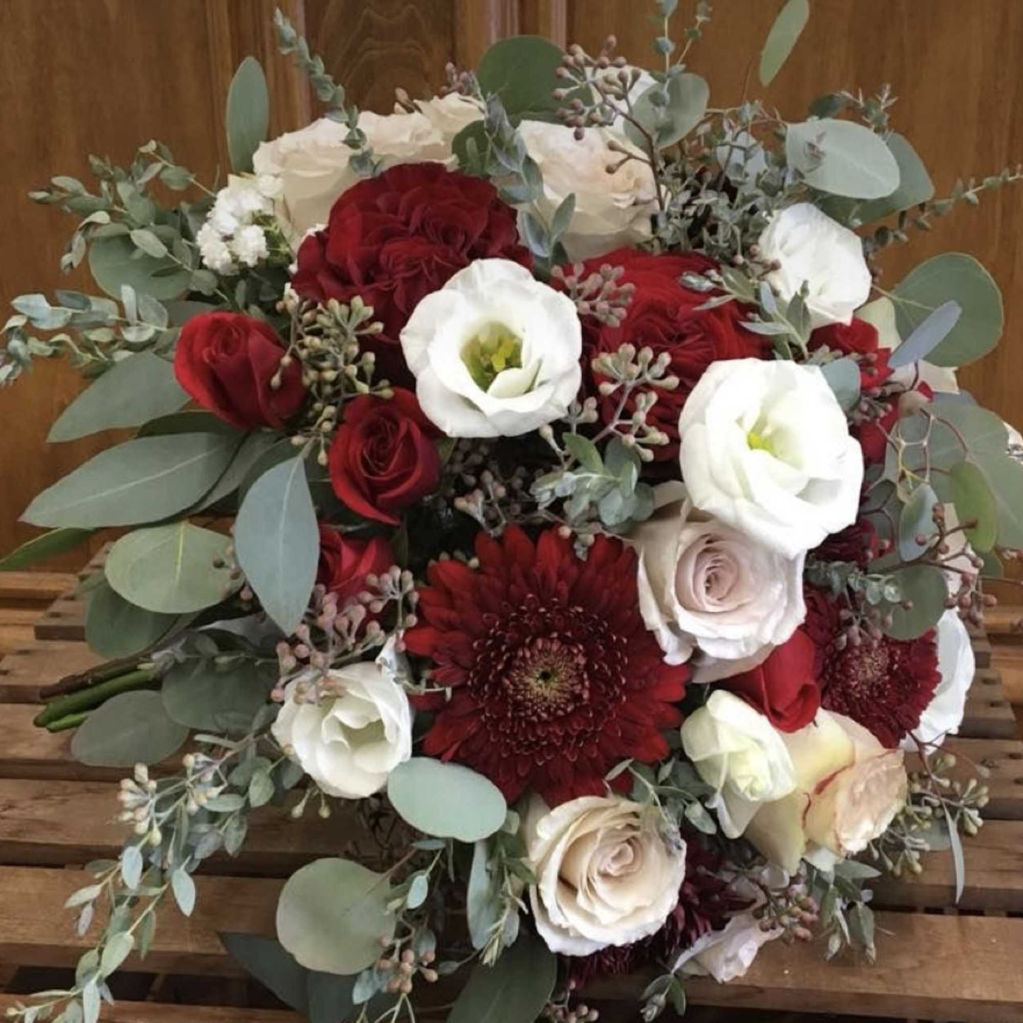 Round bouquet of red and white flowers with eucalyptus greenery