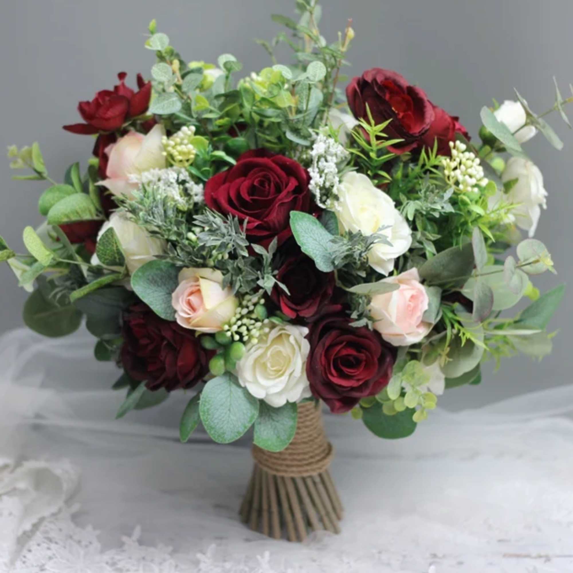 Bouquet of red and white roses with greenery in a wrapped handle