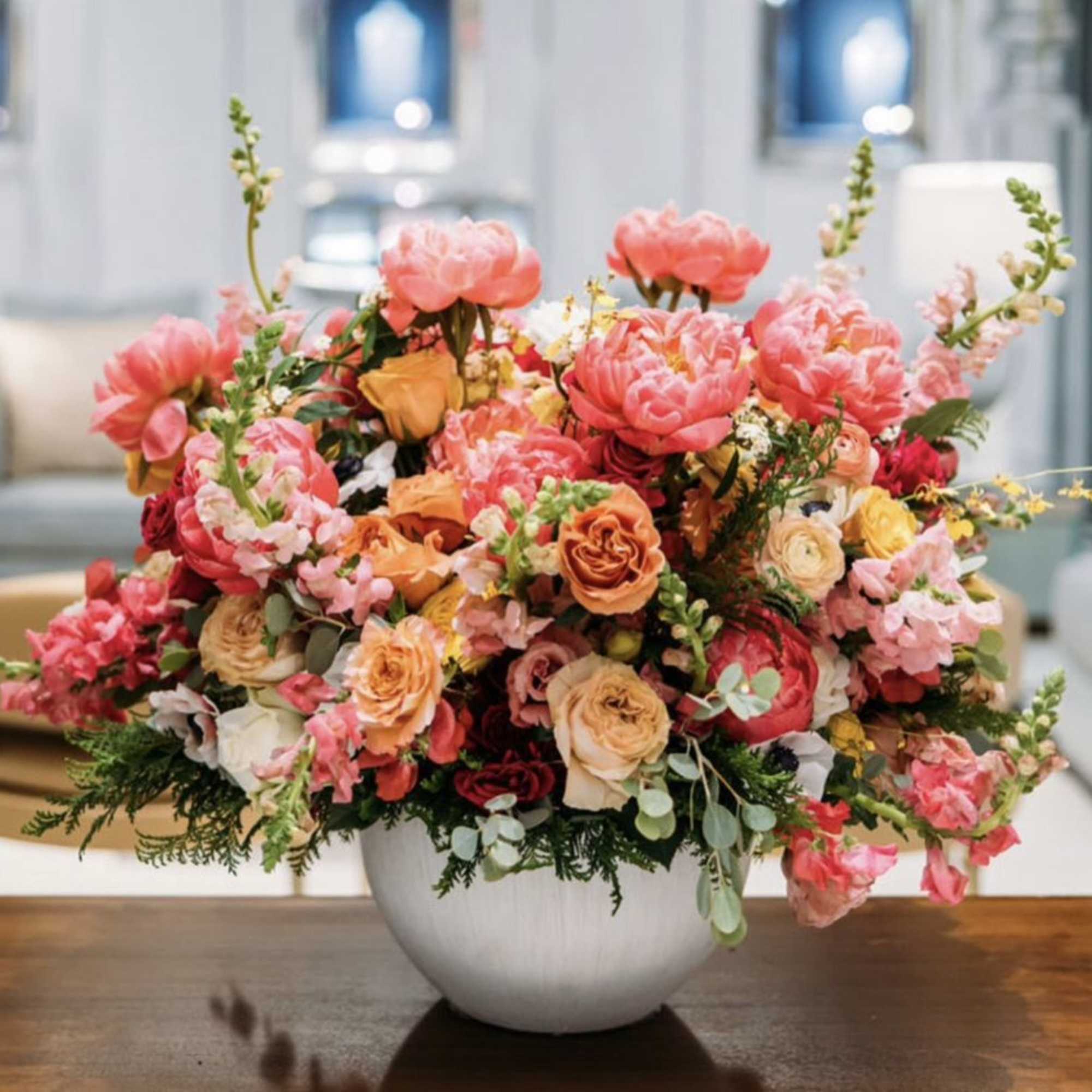 Large pink and peach floral arrangement in a white vase