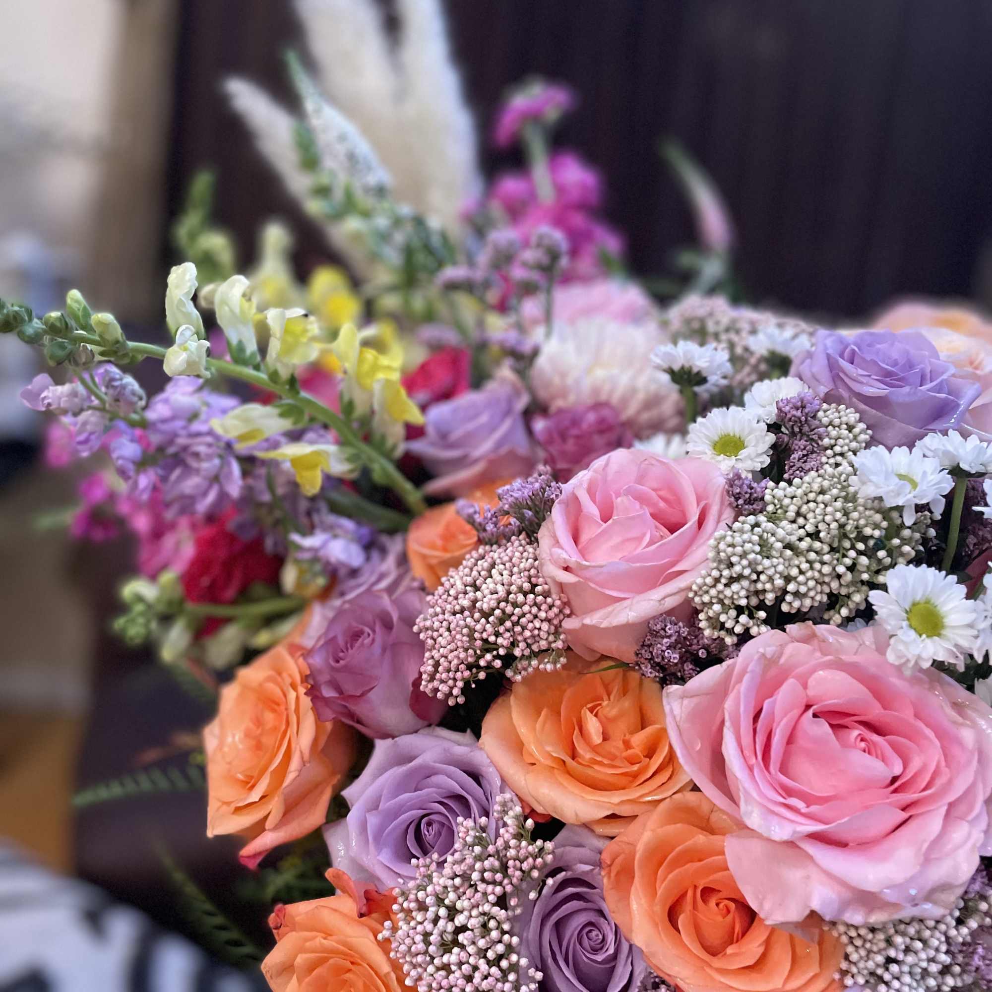 Bouquet of pink, lavender, and orange roses with small white daisies