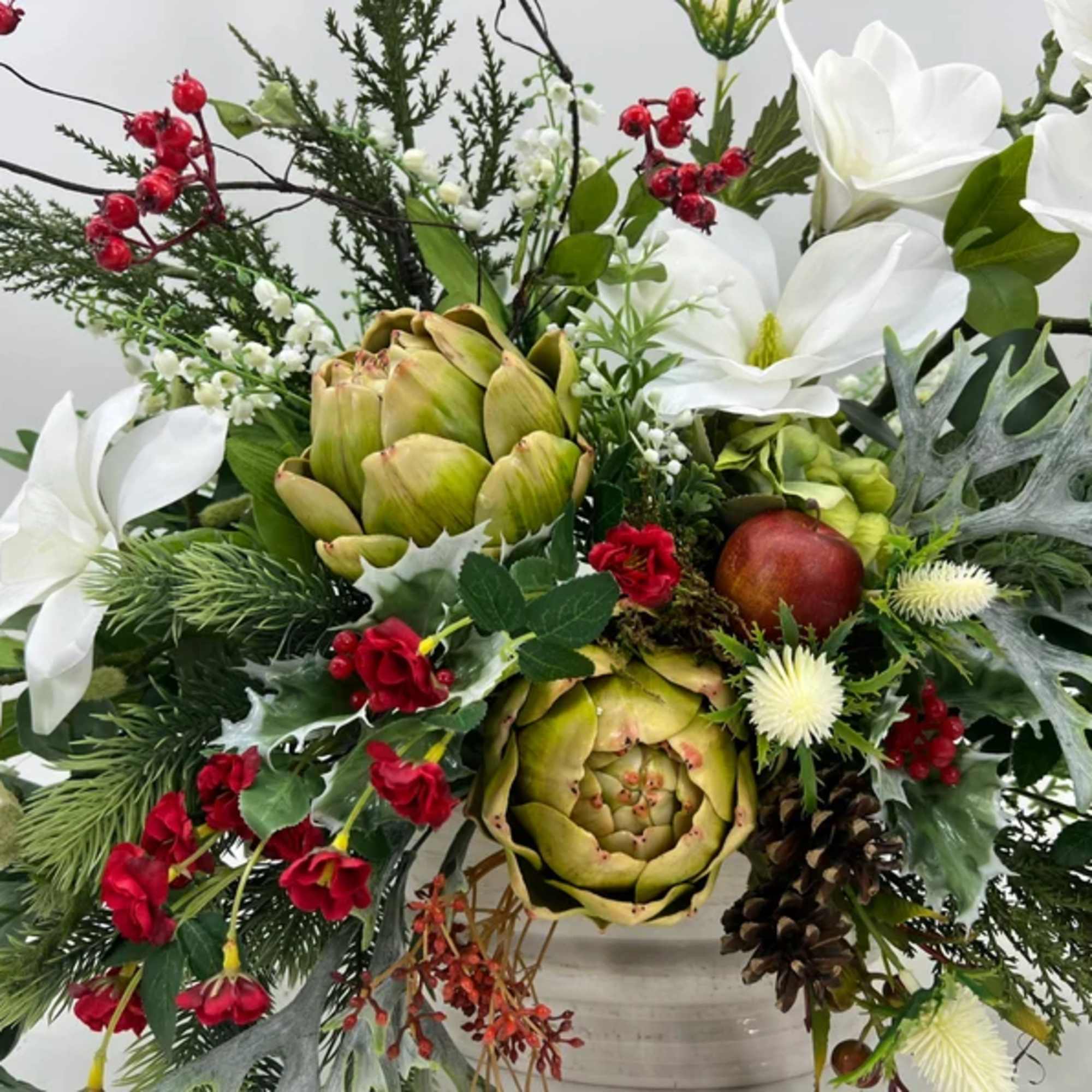 White flowers and artichokes in a festive holiday arrangement