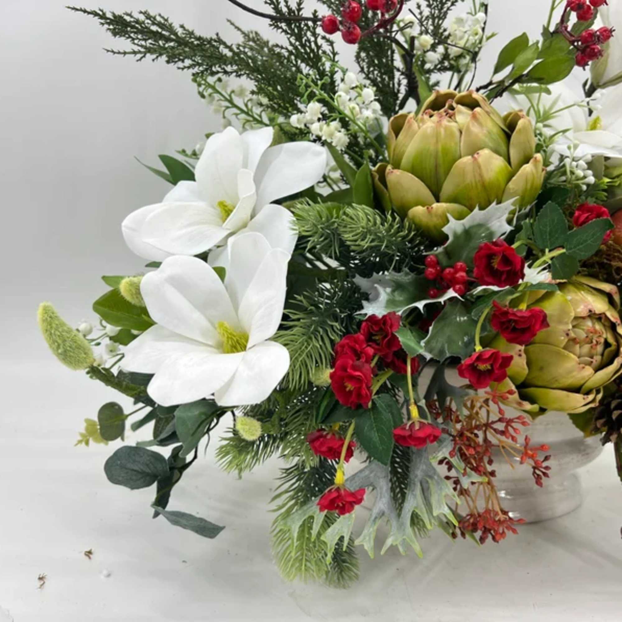 White magnolia-like blooms and red accents in a vase arrangement
