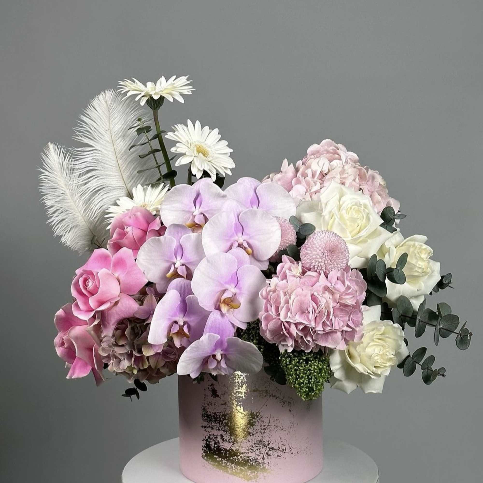 Pink and white floral arrangement in a pink cylindrical box