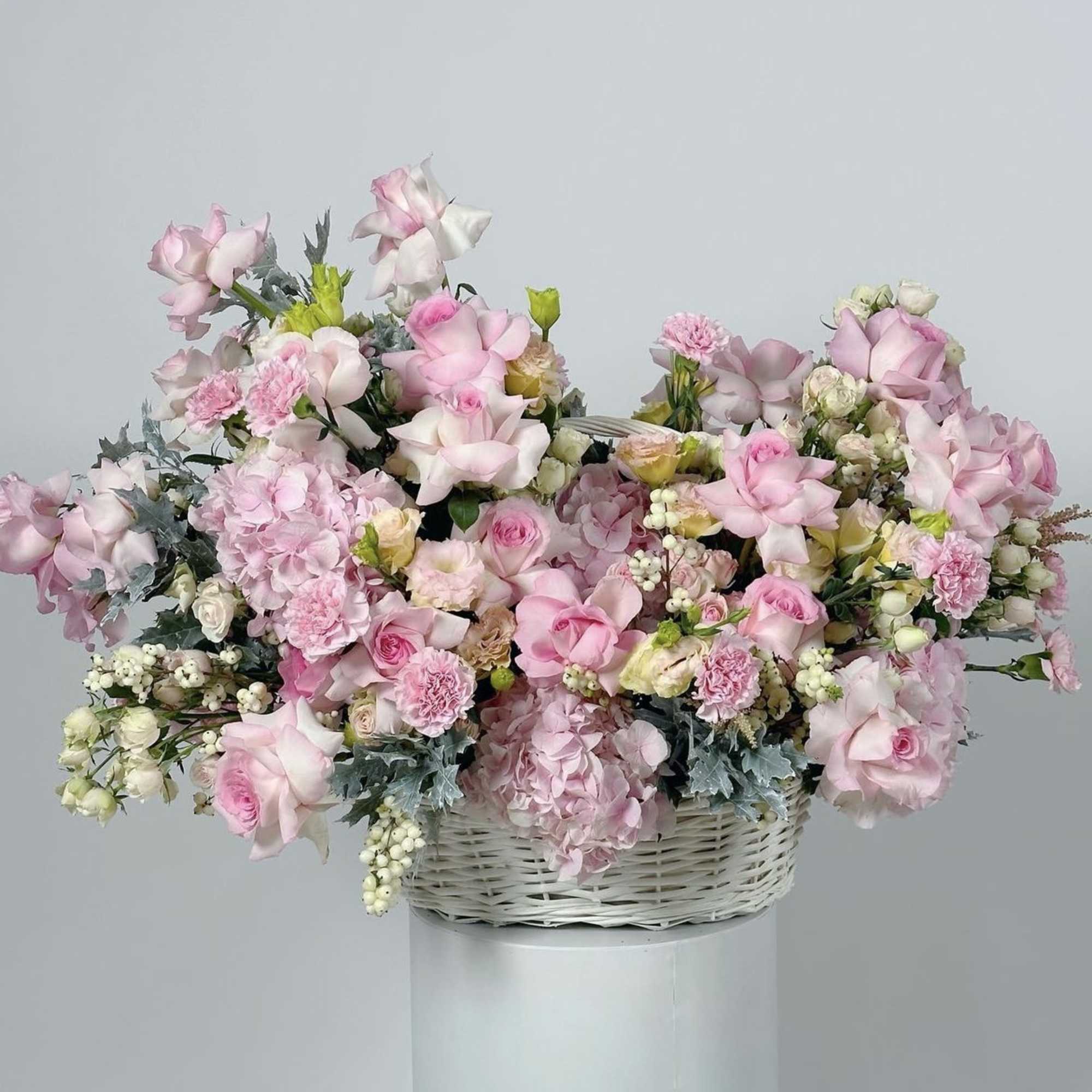 Pink and white floral arrangement in a white wicker basket
