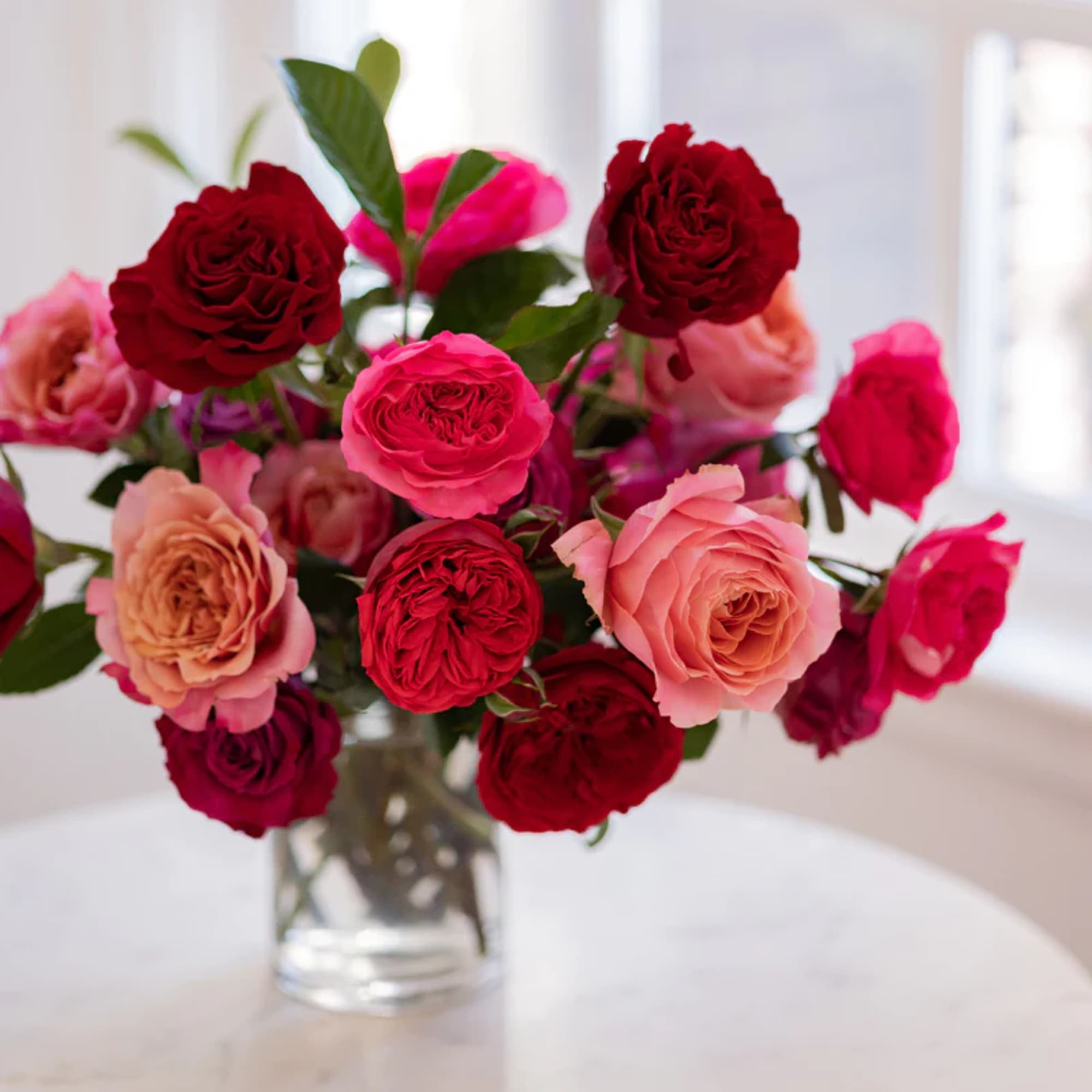 Bouquet of red, pink, and peach roses in a clear glass vase, photo 2 of 3