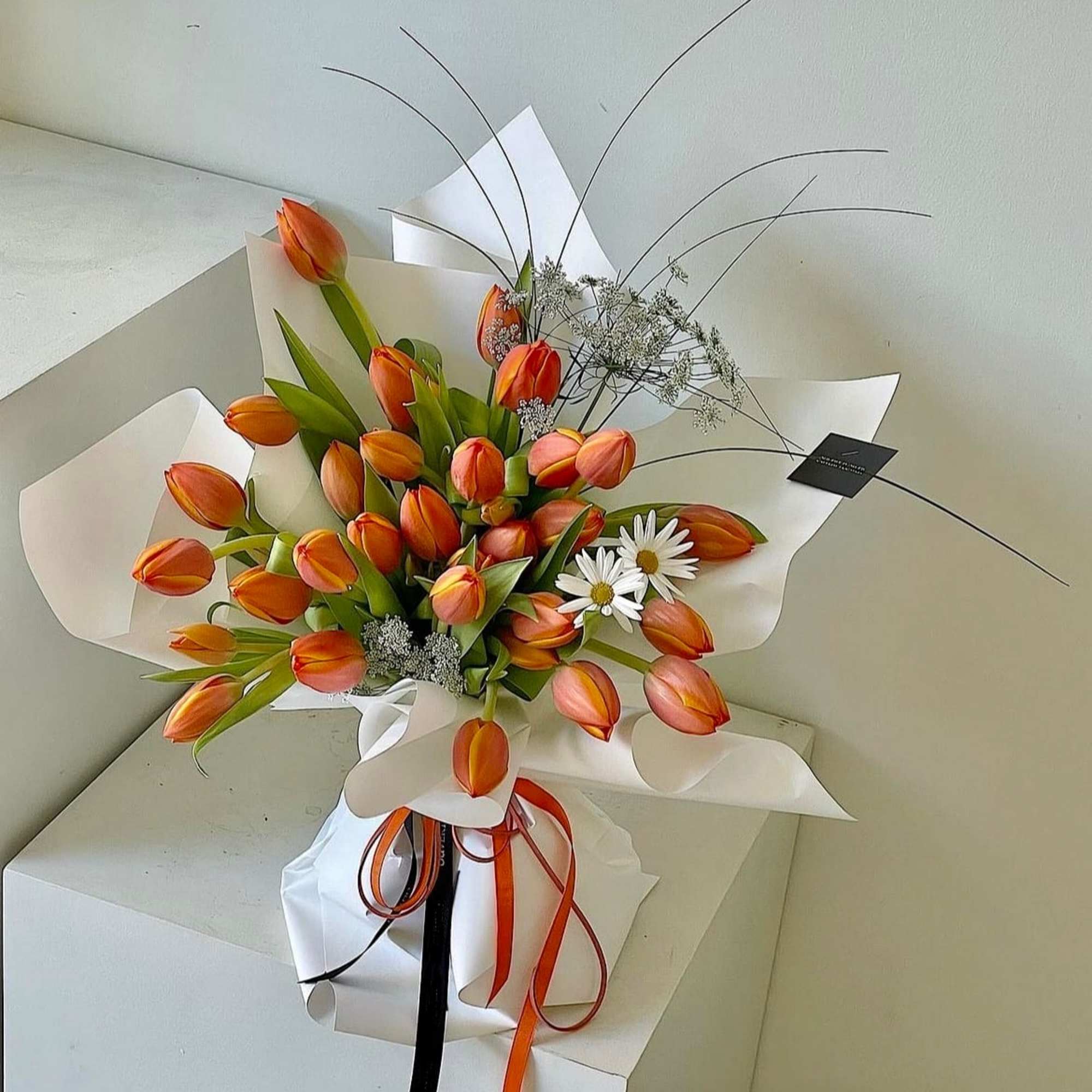 Orange tulip bouquet with white daisies and ribbon wrap