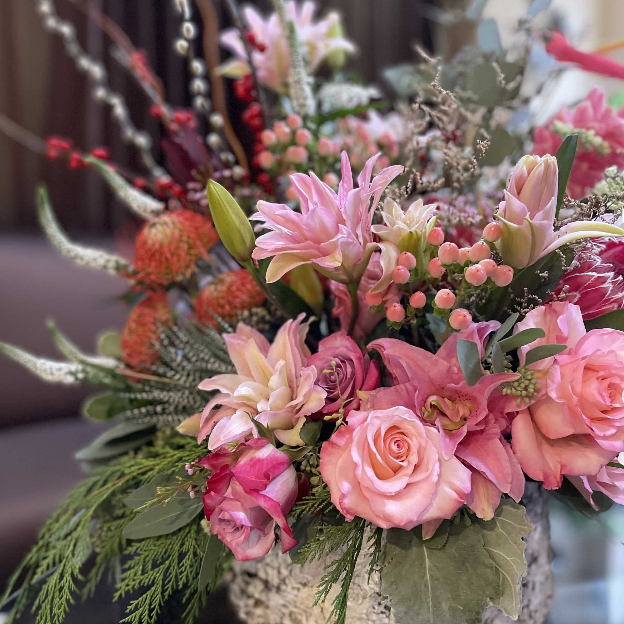 Pink roses and lilies arranged in a rustic round container