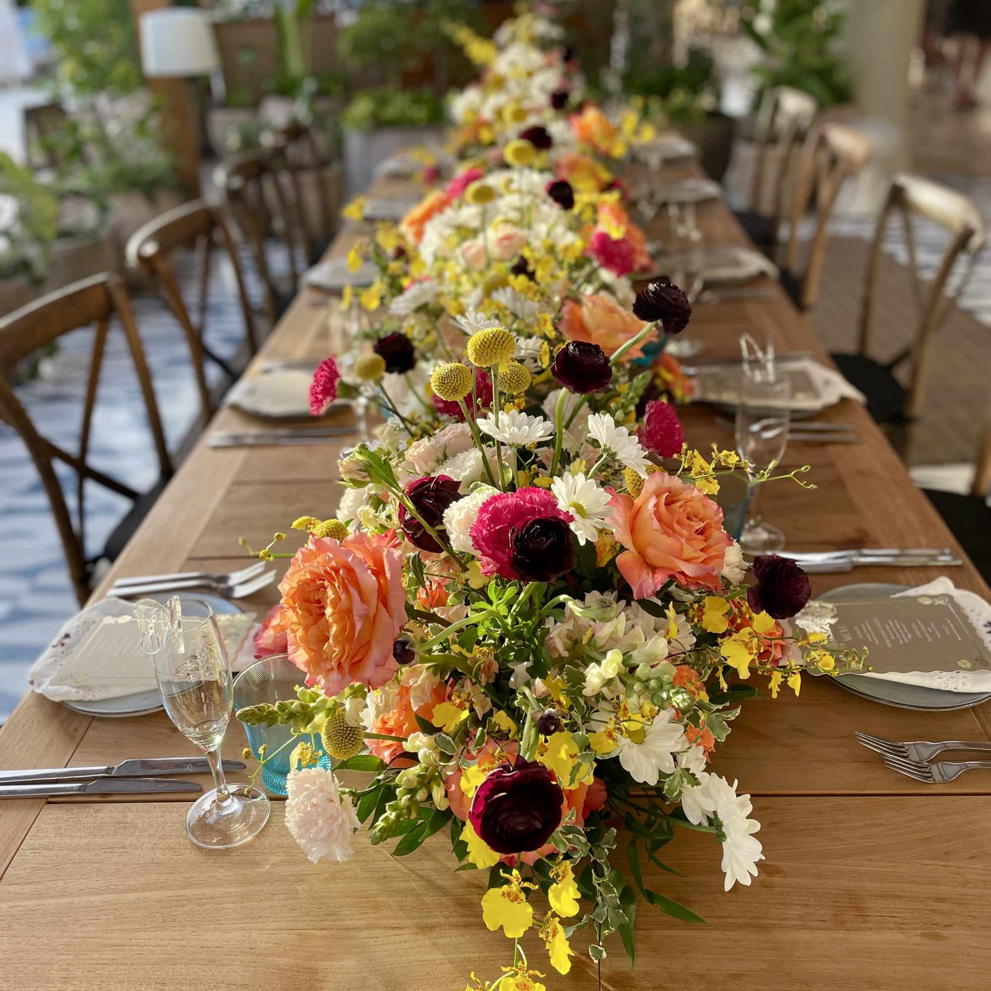 Long table with colorful floral centerpieces and place settings