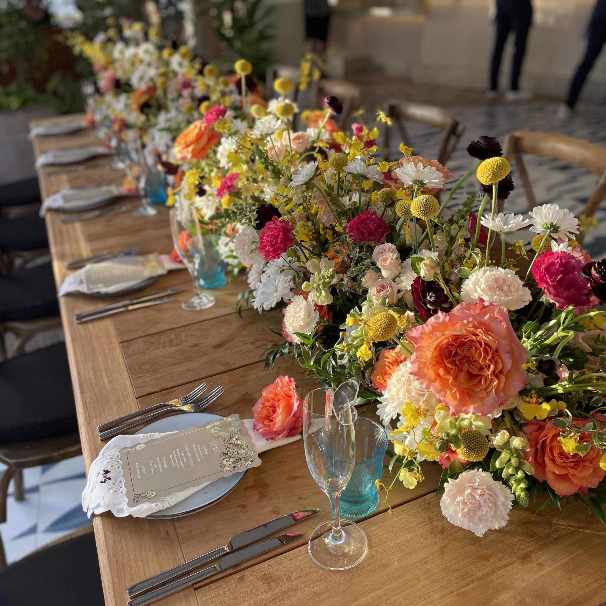Long banquet table with colorful floral centerpieces and place settings