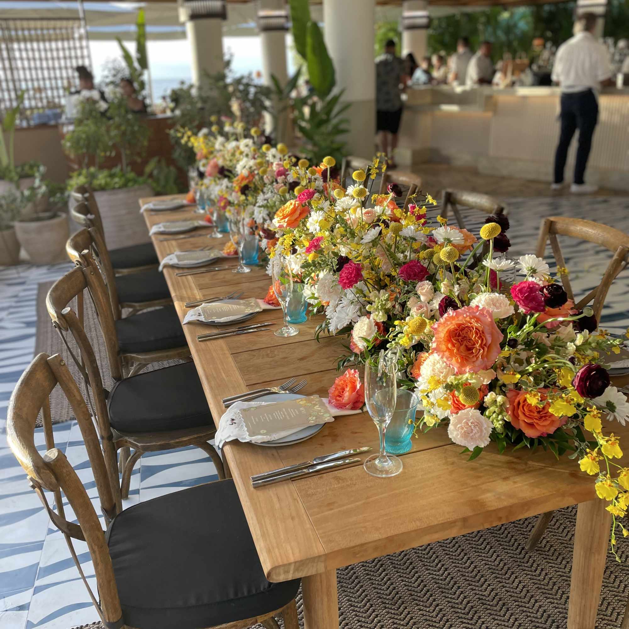 Long banquet table with colorful flower centerpieces in a resort setting