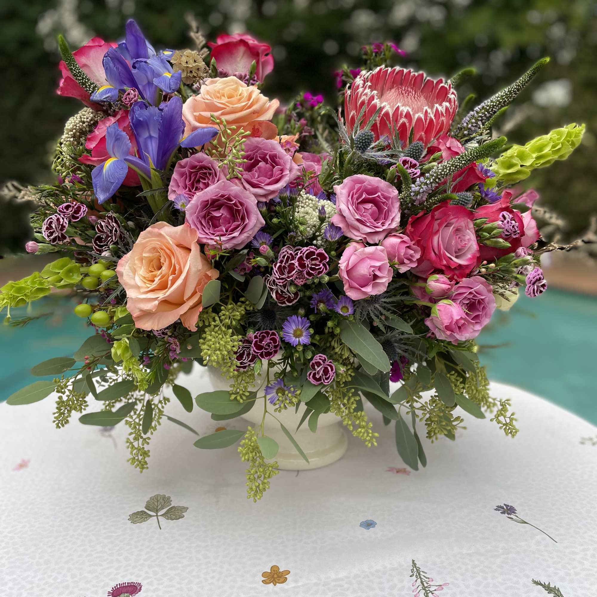 Colorful mixed flower arrangement in a white vase on a patterned tablecloth