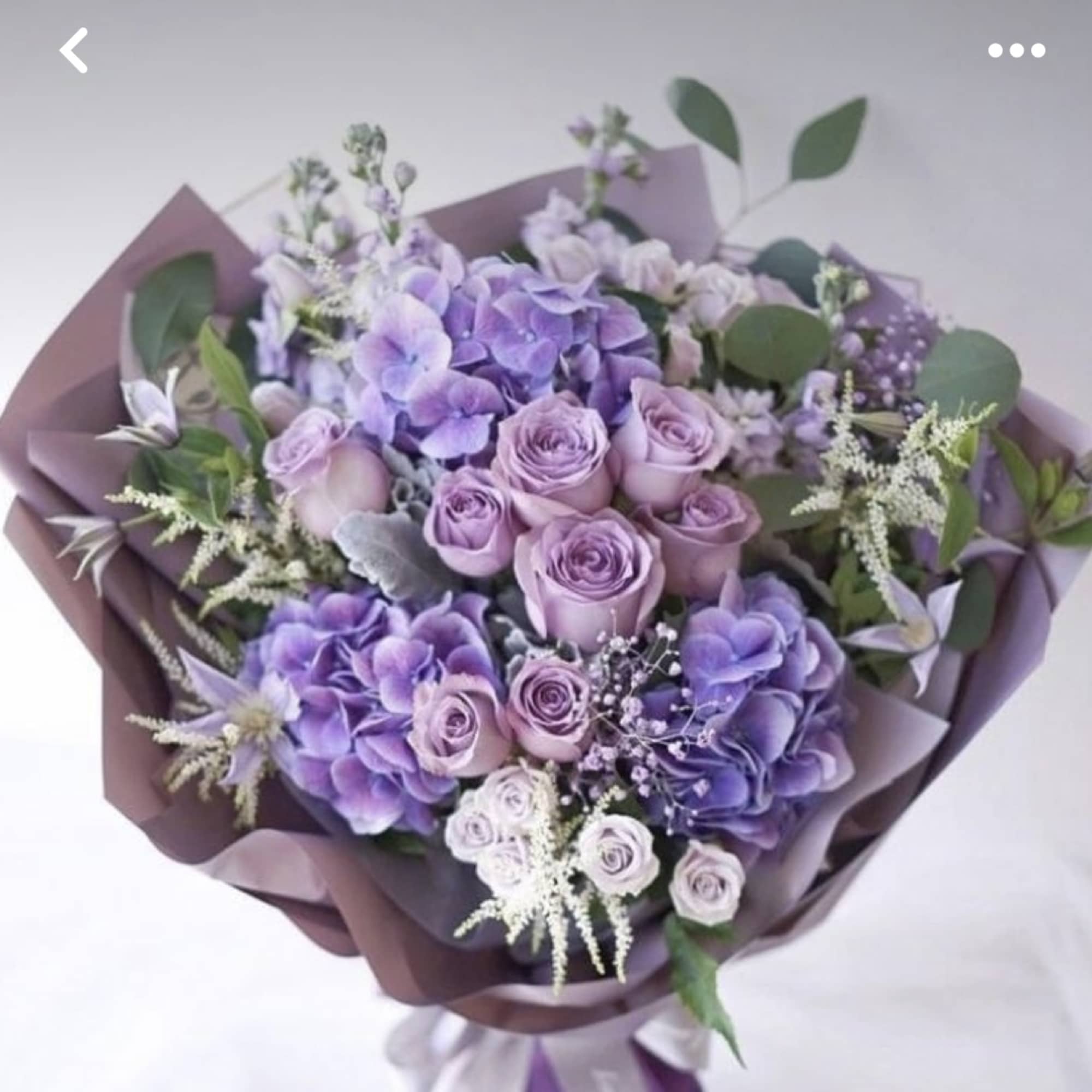 Lavender and purple bouquet of roses and hydrangeas wrapped in mauve paper
