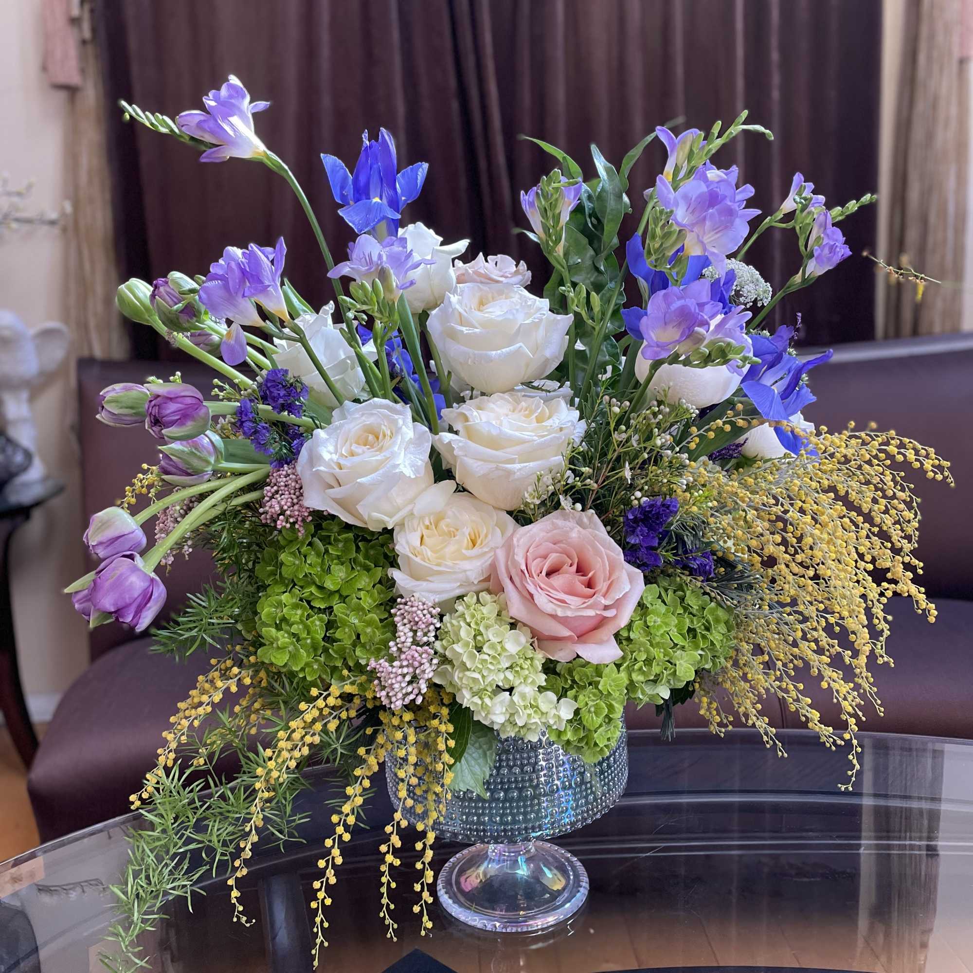 Mixed bouquet of white and pink roses with purple blooms in a glass vase