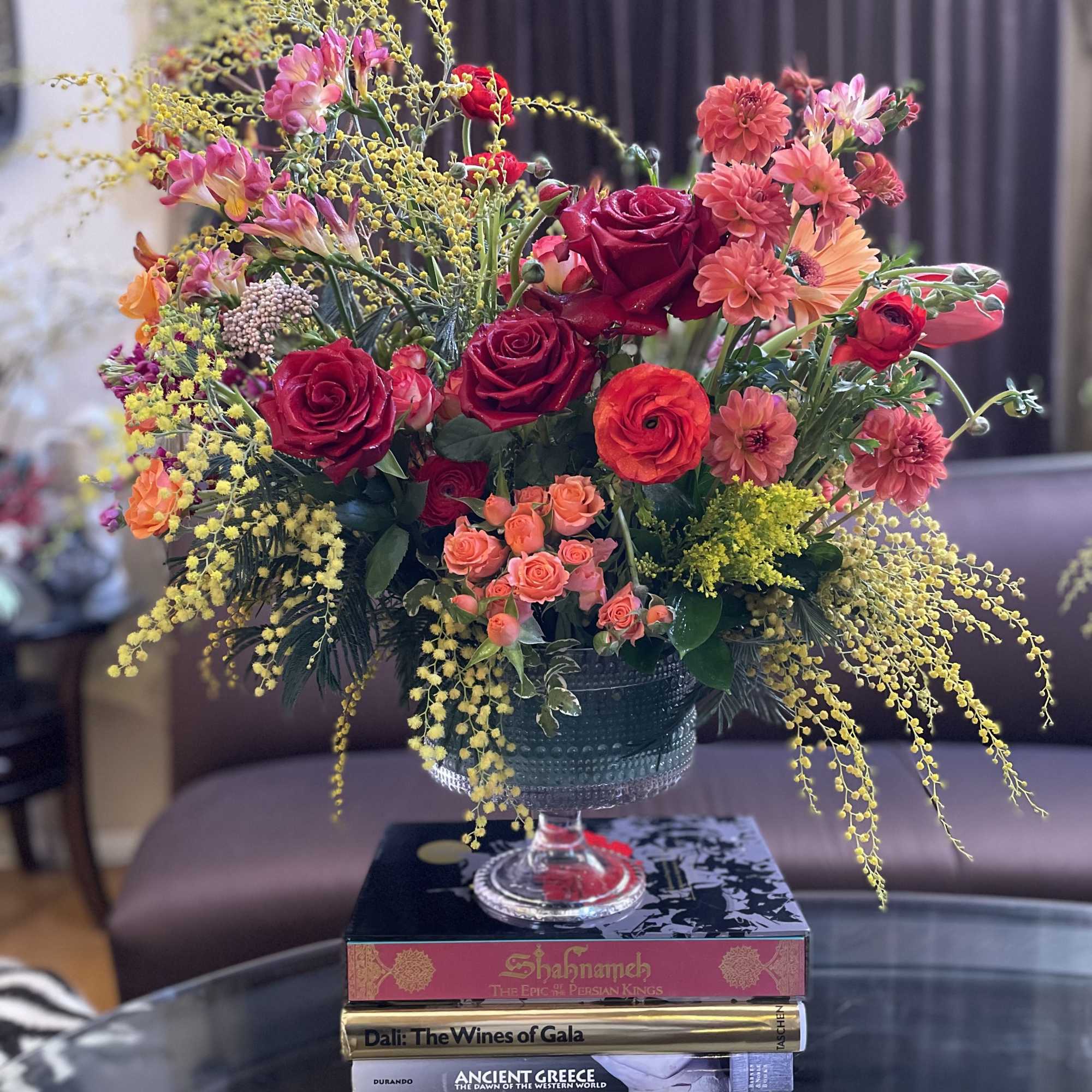 Mixed bouquet of red and pink flowers in a glass compote vase