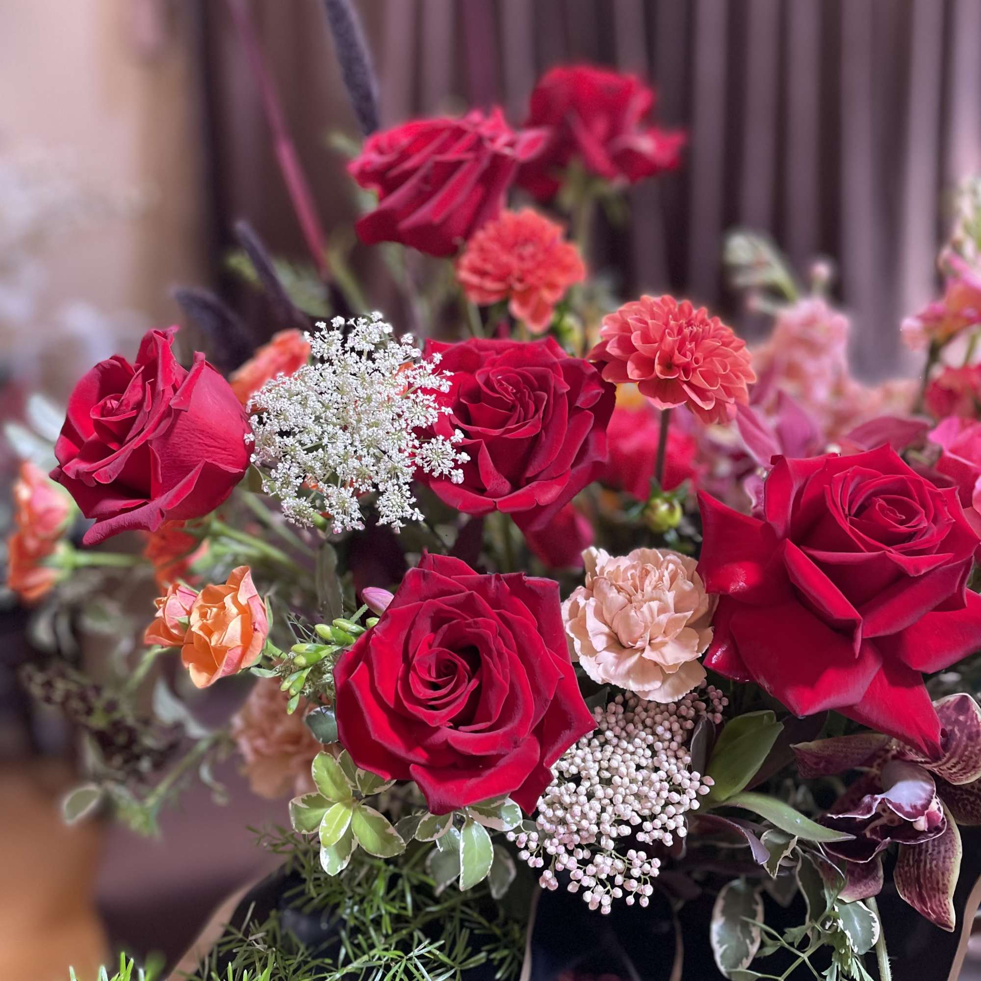 Bouquet of red roses and peach carnations in a dark wrap
