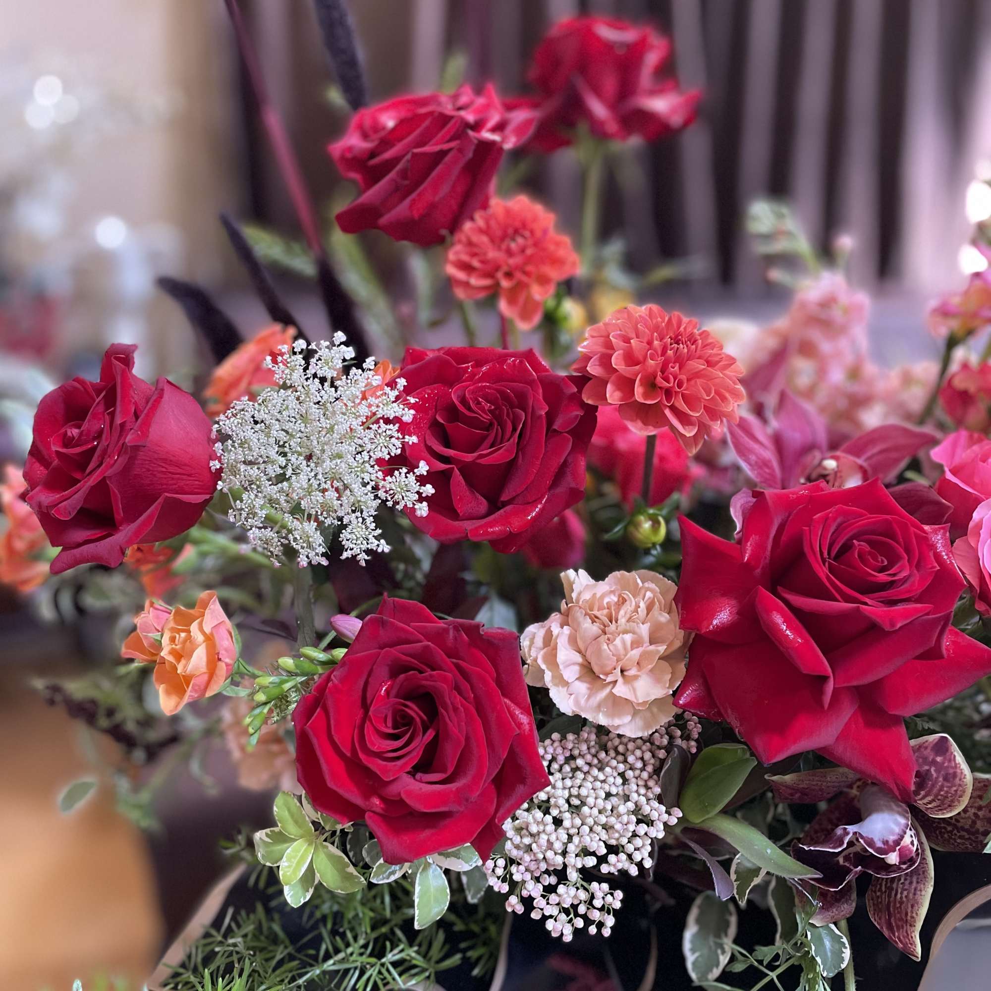 Bouquet of red roses and coral blooms with white filler flowers