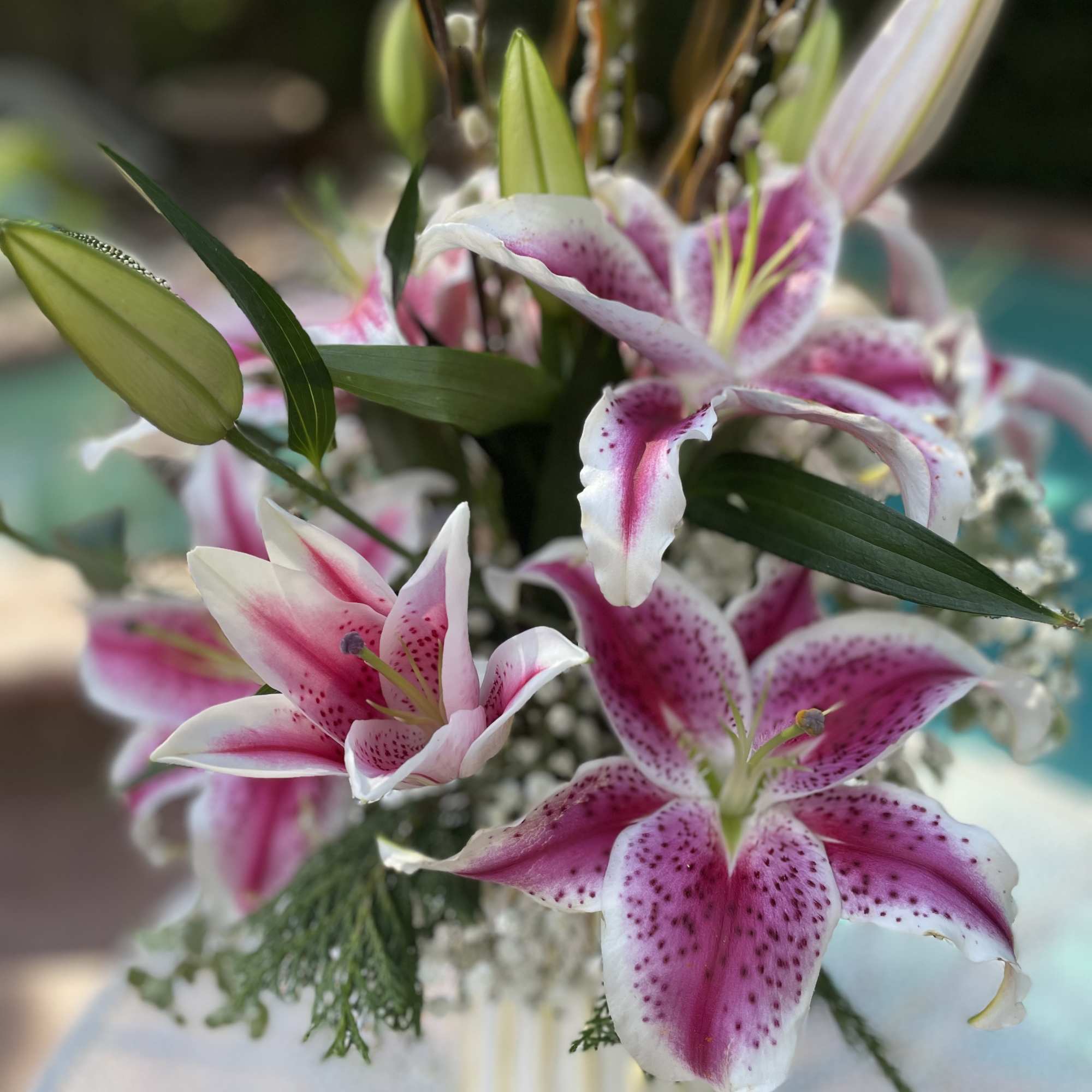 Pink stargazer lilies in a glass vase with buds and greenery