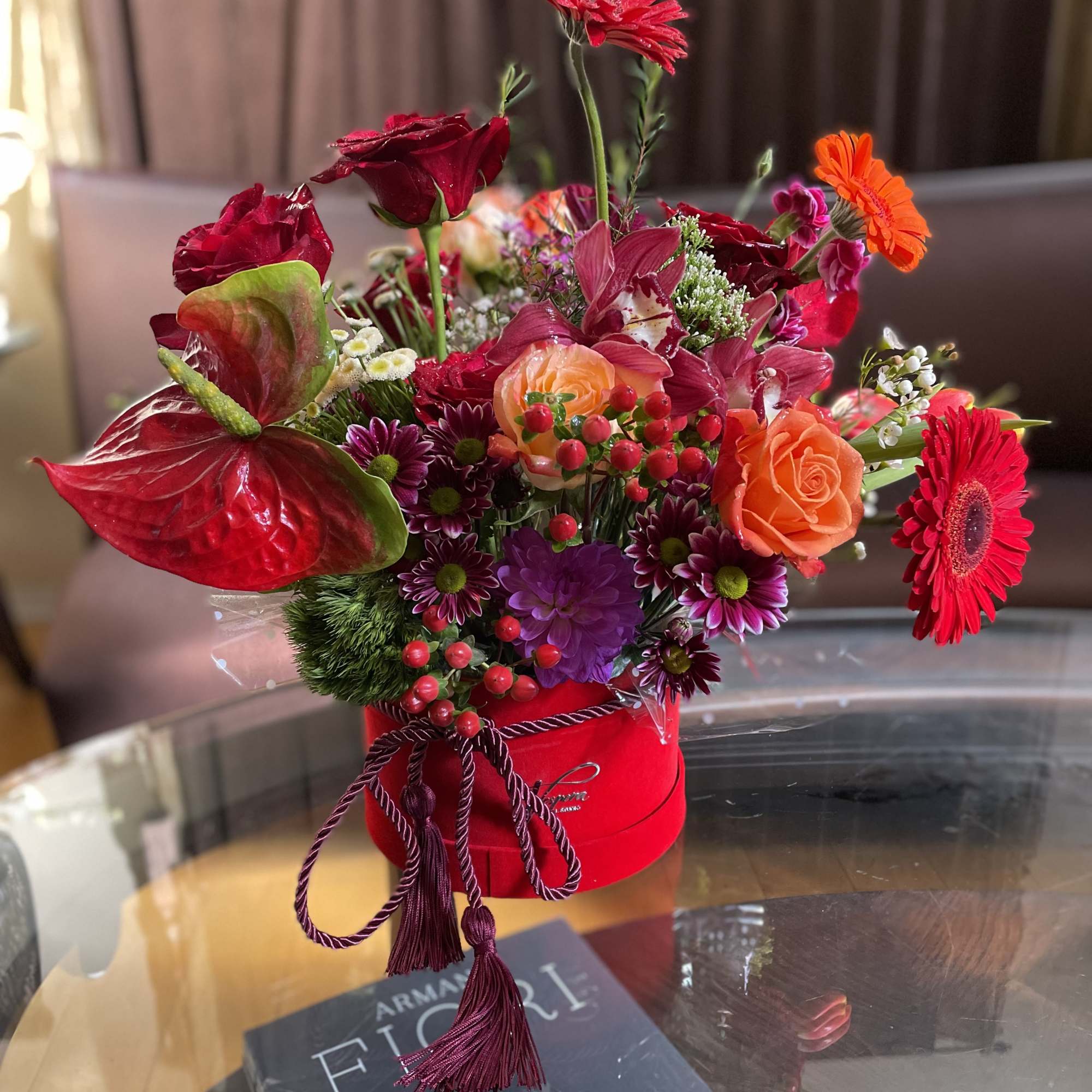 Bright mixed flower arrangement in a red hat box with roses and gerbera daisies