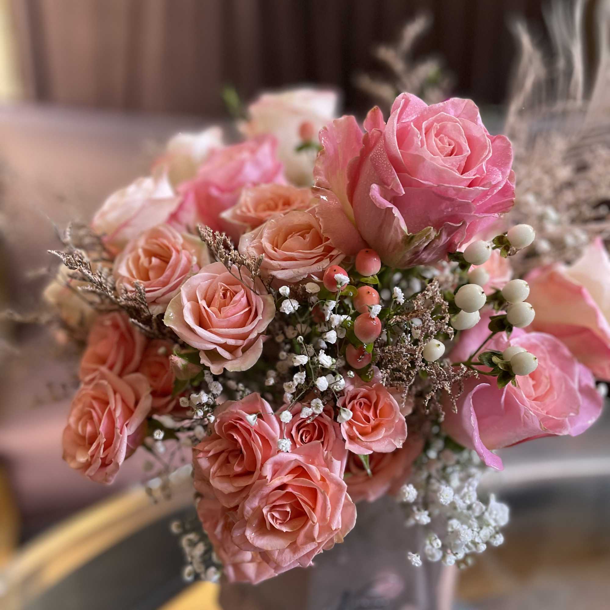 Pink and peach rose bouquet with baby's breath and berry accents