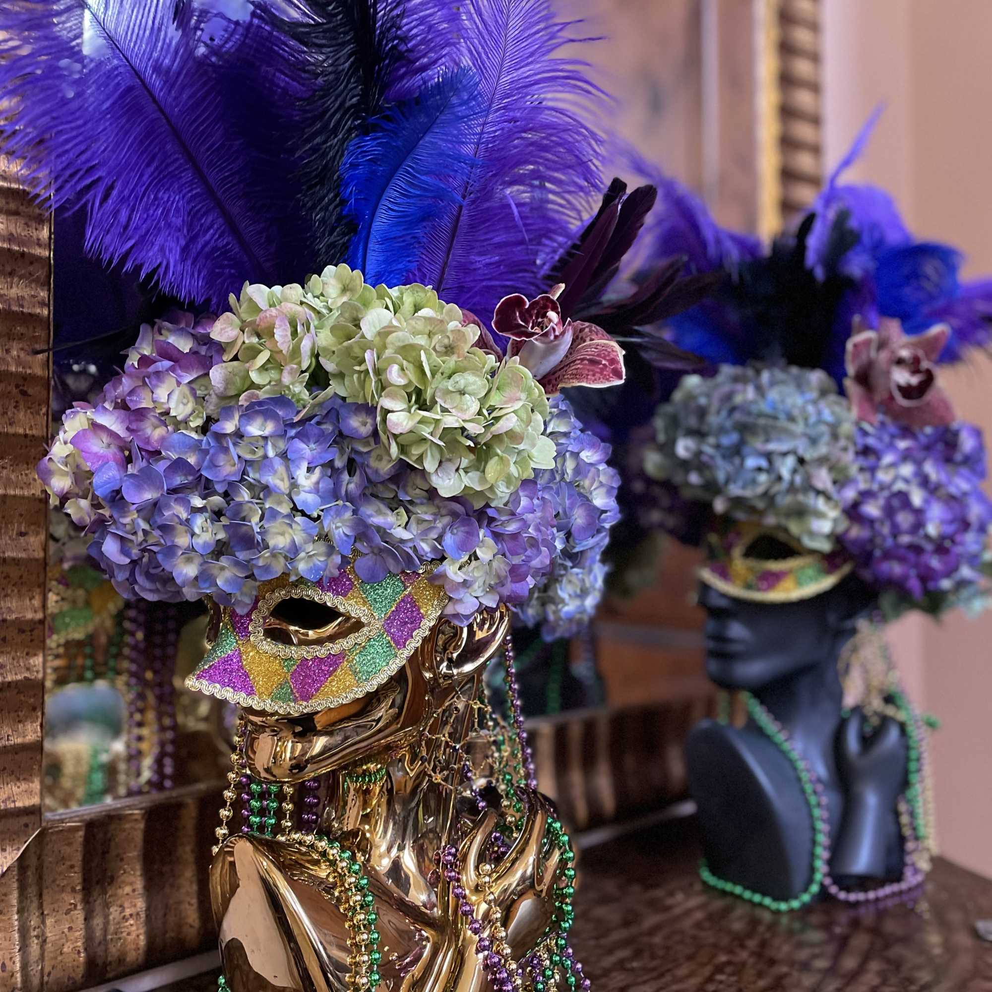 Decorative mask topped with purple hydrangeas and feathers