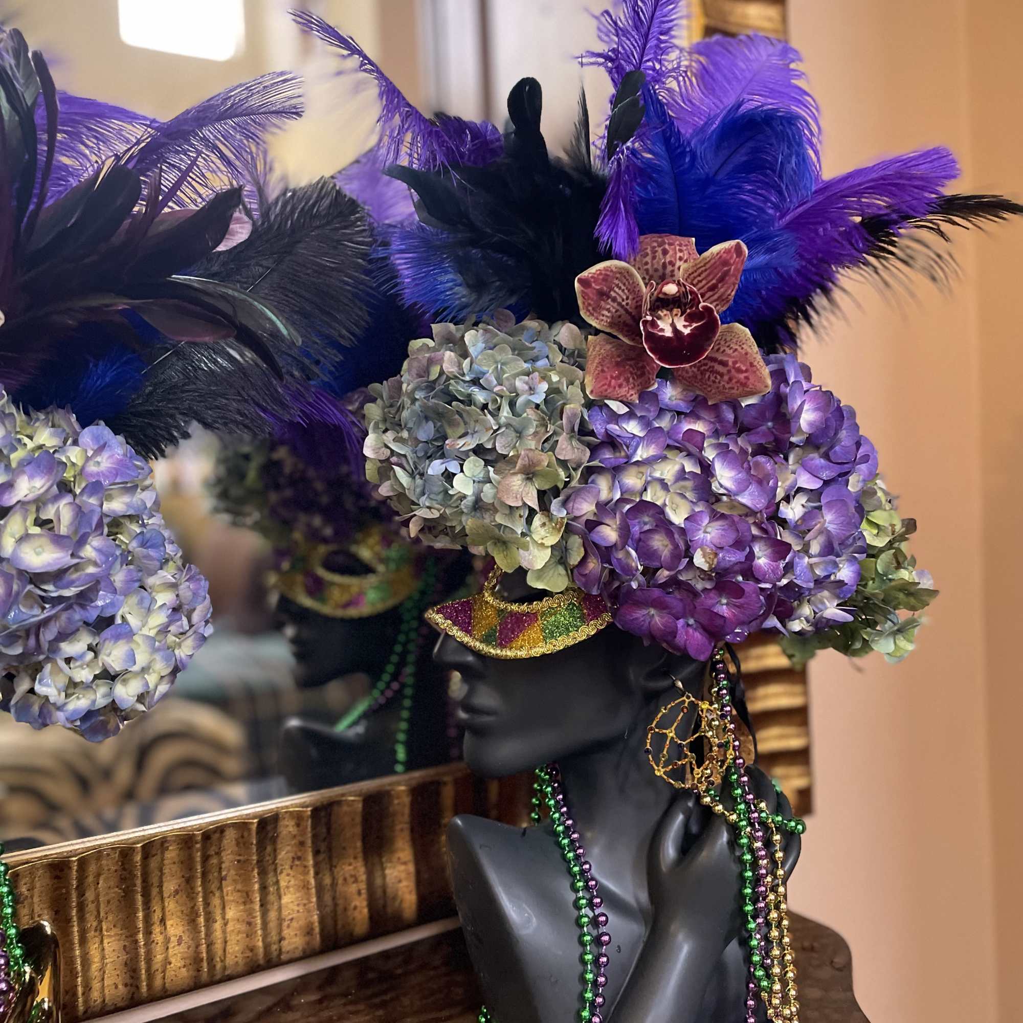 Purple hydrangea headpiece on a black mannequin bust with feathers and beads